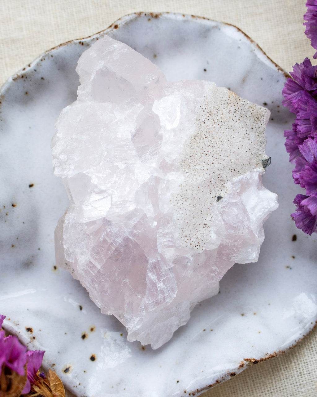 Crystal rock on a textured surface with purple flowers