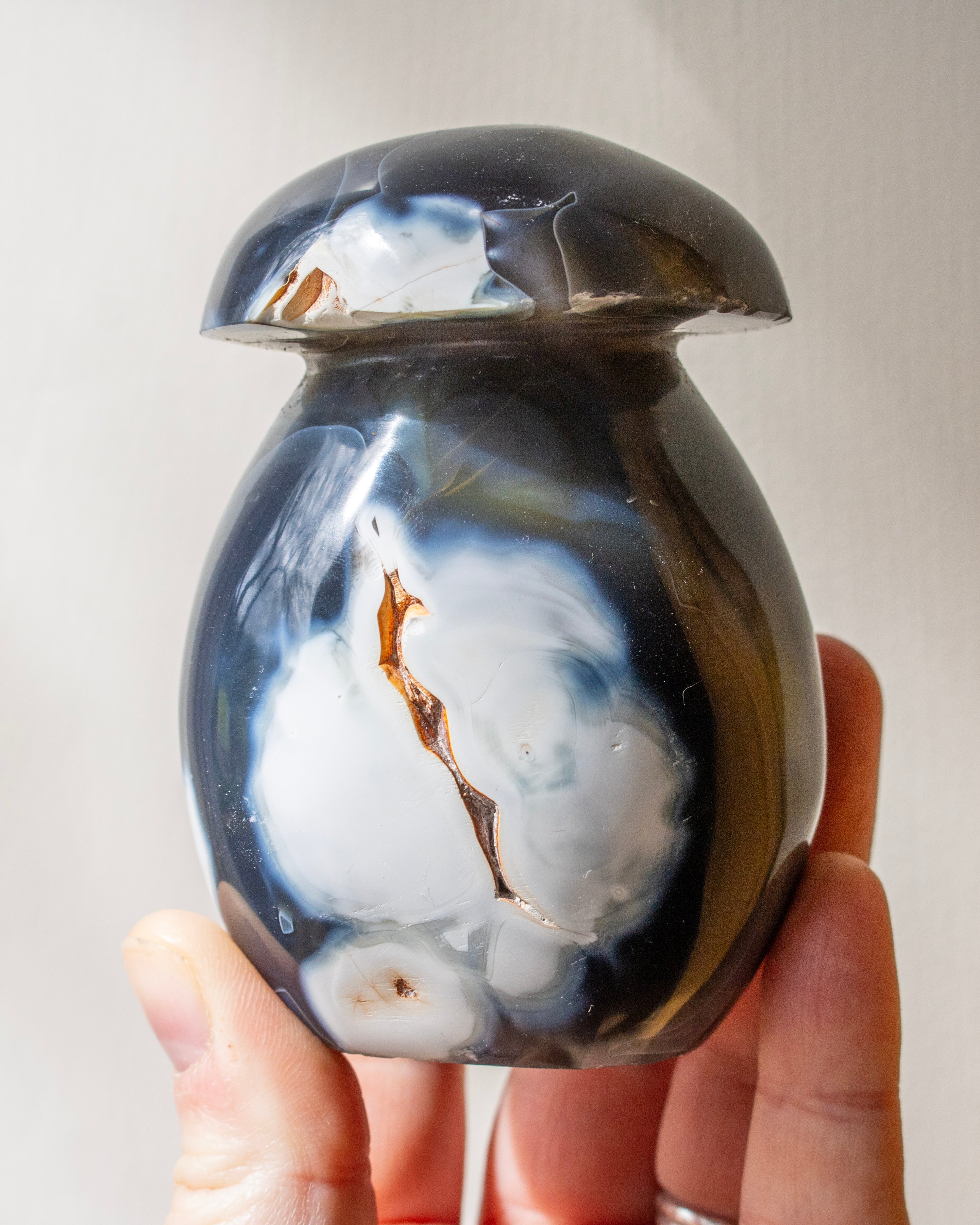 Hand holding a agate with marbled design on a plain background