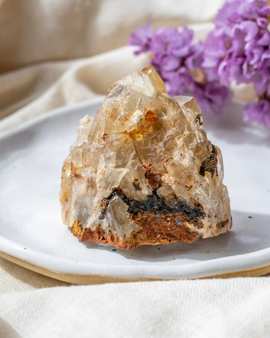 Crystal rock on a white plate with purple flowers in the background