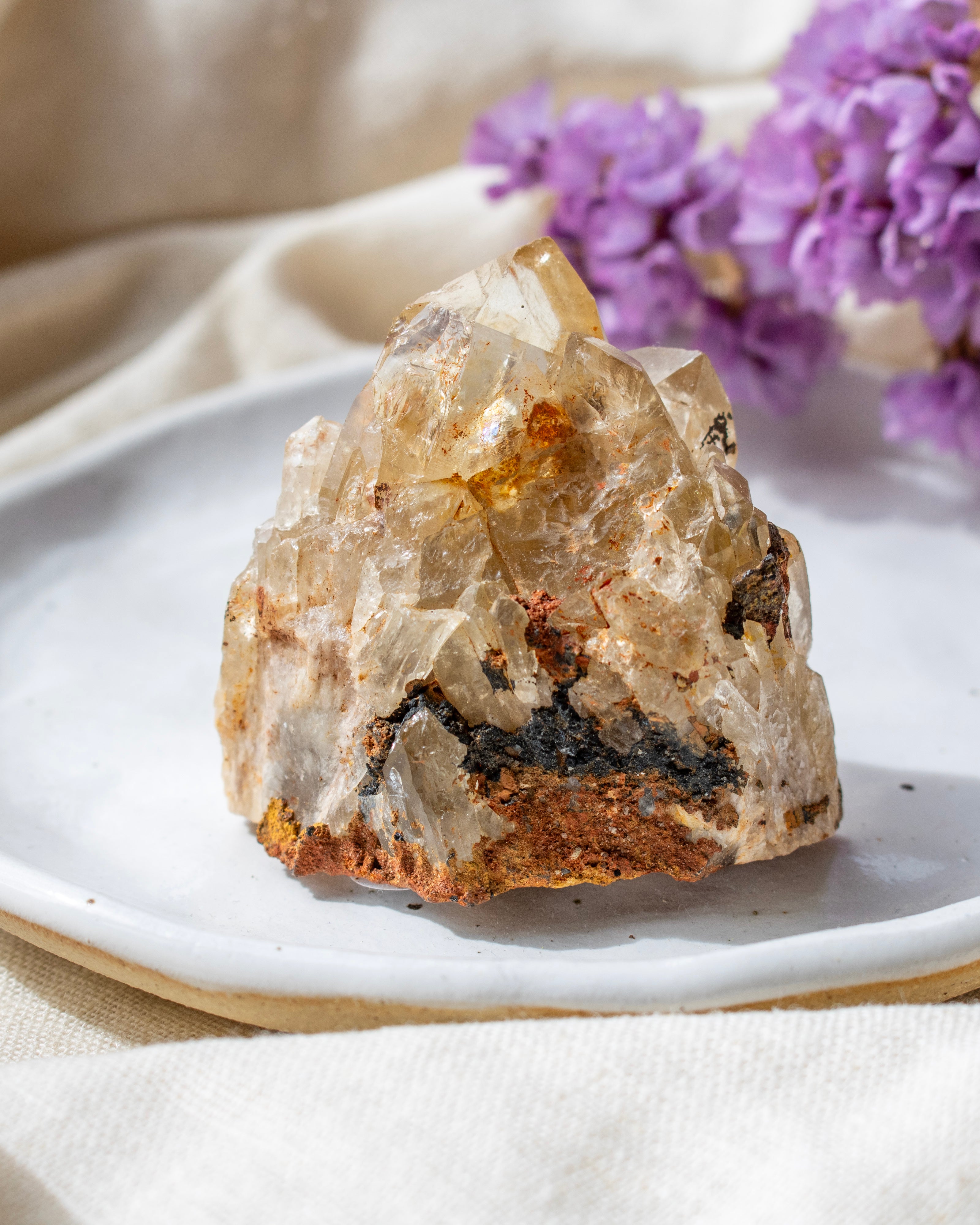 Crystal rock on a white plate with purple flowers in the background