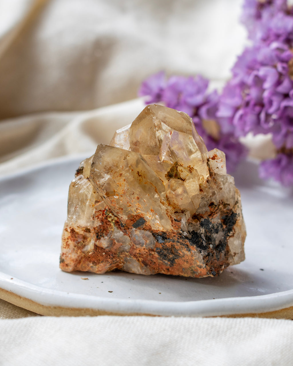 Crystal rock on a white plate with purple flowers in the background
