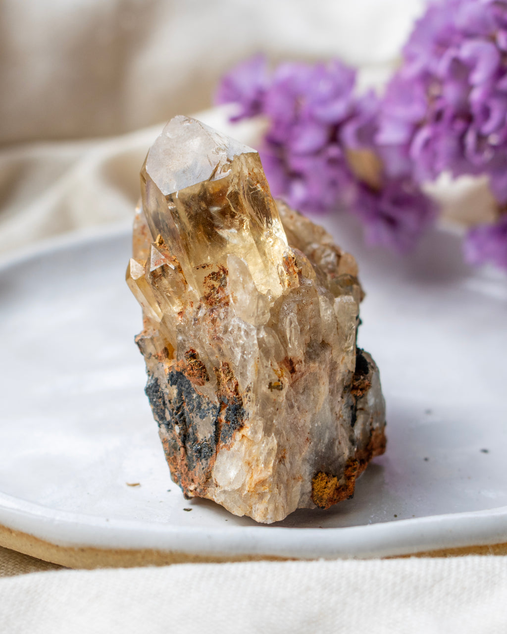 Crystal on a white plate with purple flowers in the background