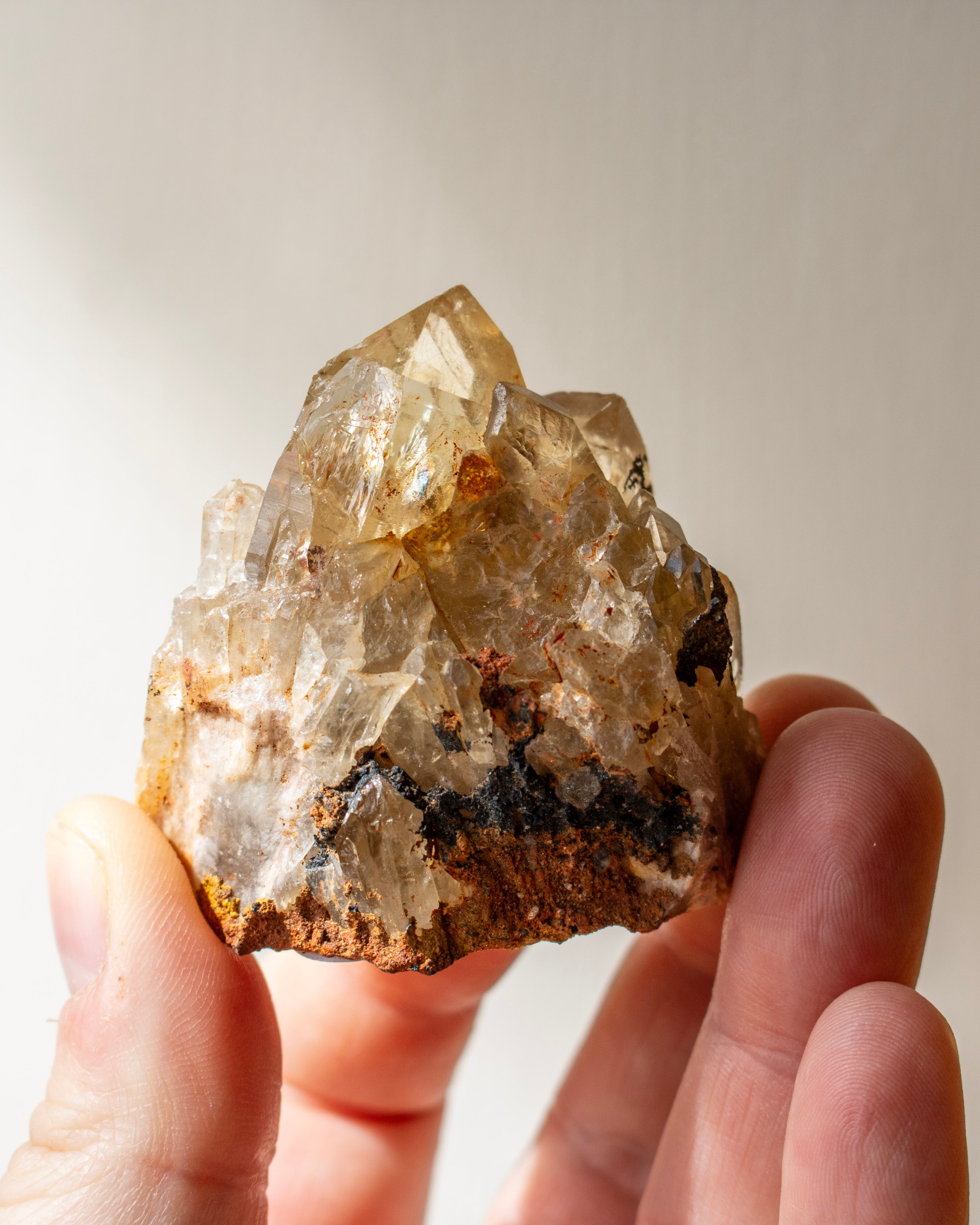 Hand holding a clear crystal rock against a neutral background