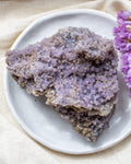 Purple crystal rock on a white plate with a purple flower