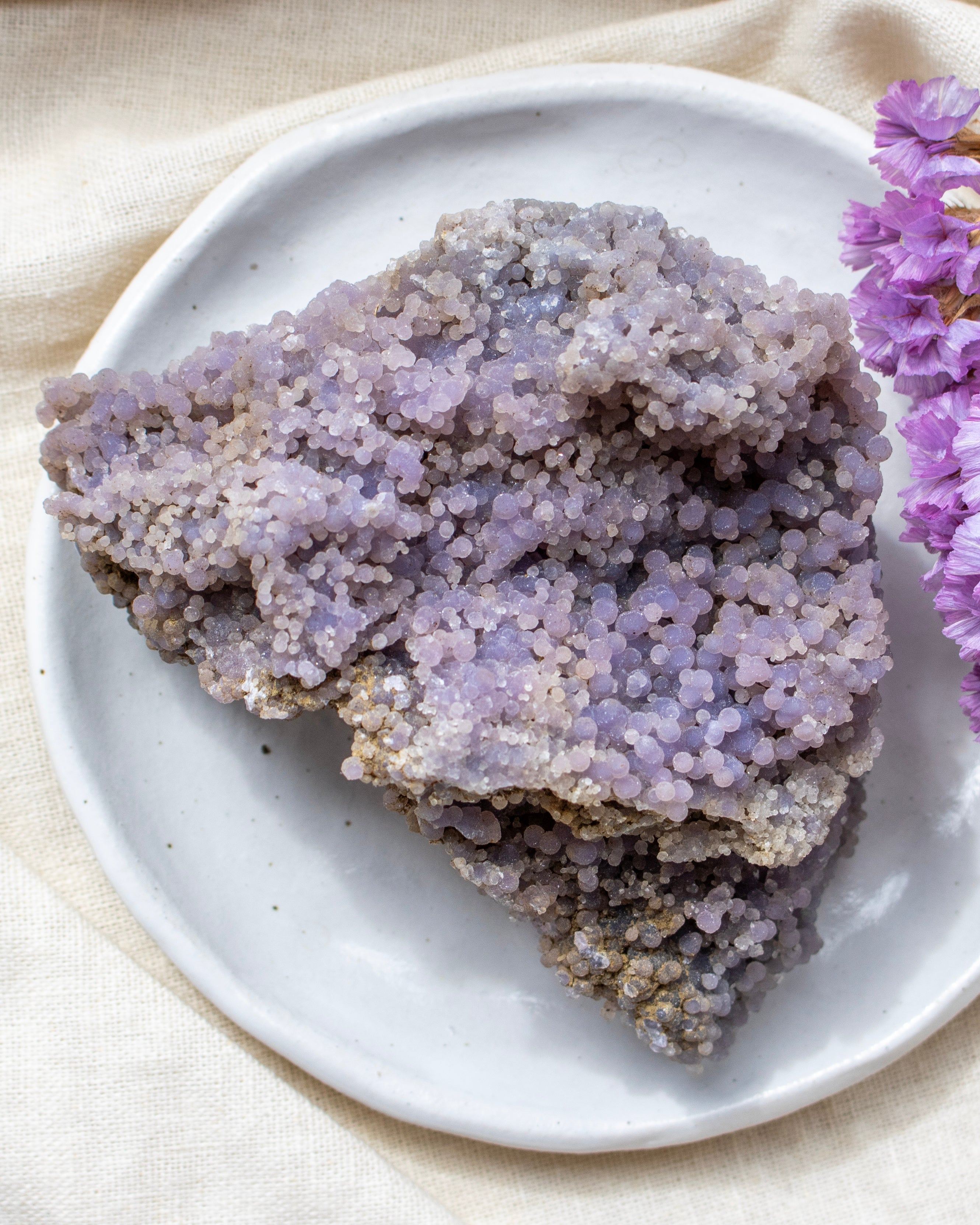 Purple crystal rock on a white plate with a purple flower