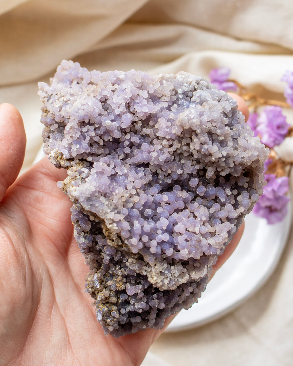 Hand holding a purple crystal rock with a blurred background