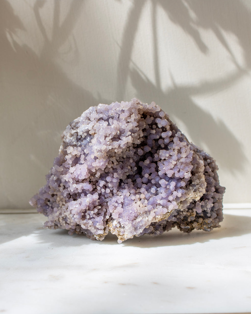 Purple crystal rock on a white surface with a light background
