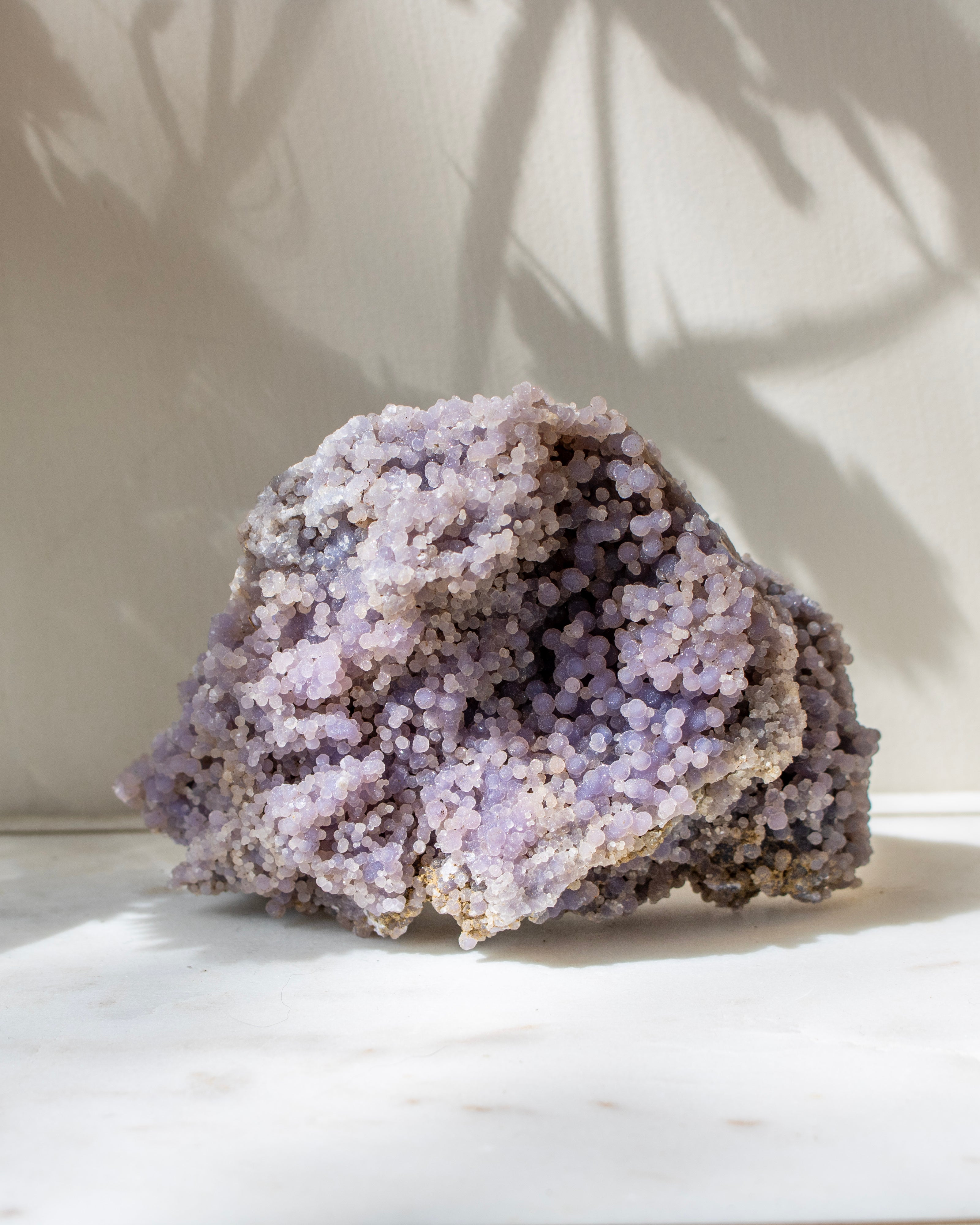Purple crystal rock on a white surface with a light background