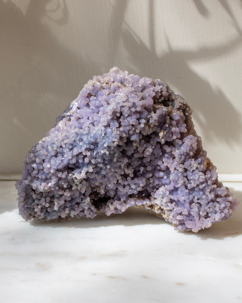 Purple crystal rock on a white marble surface with a neutral background