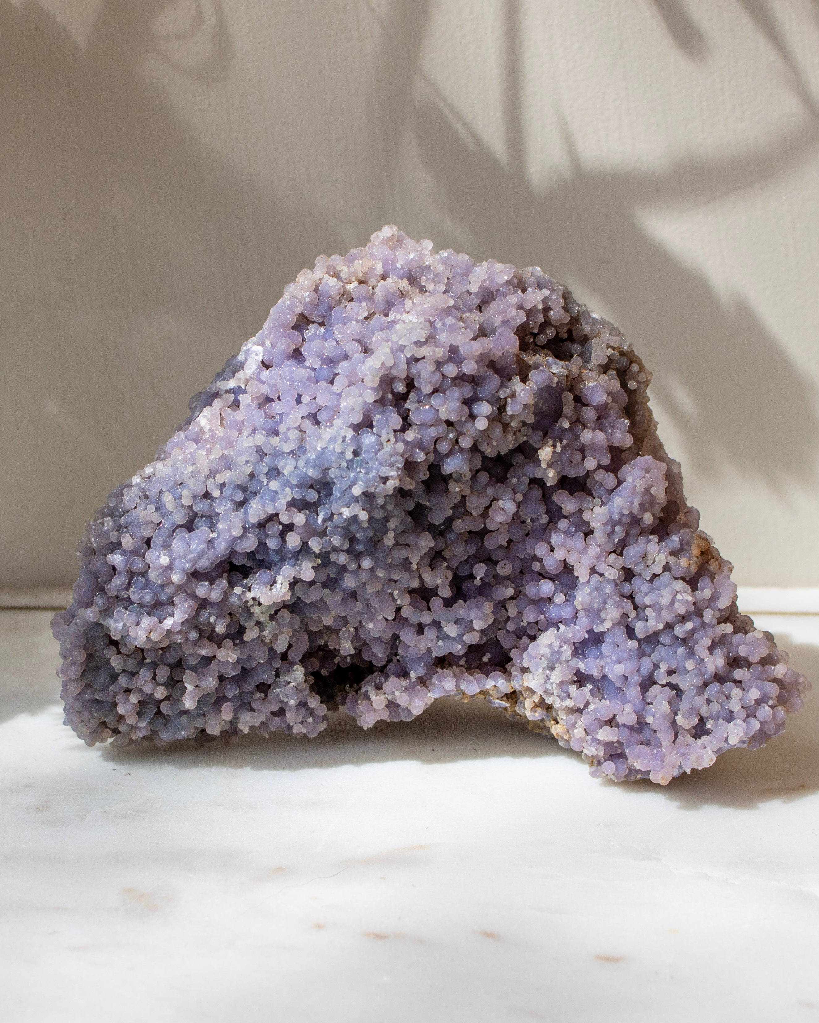 Purple crystal rock on a white marble surface with a neutral background