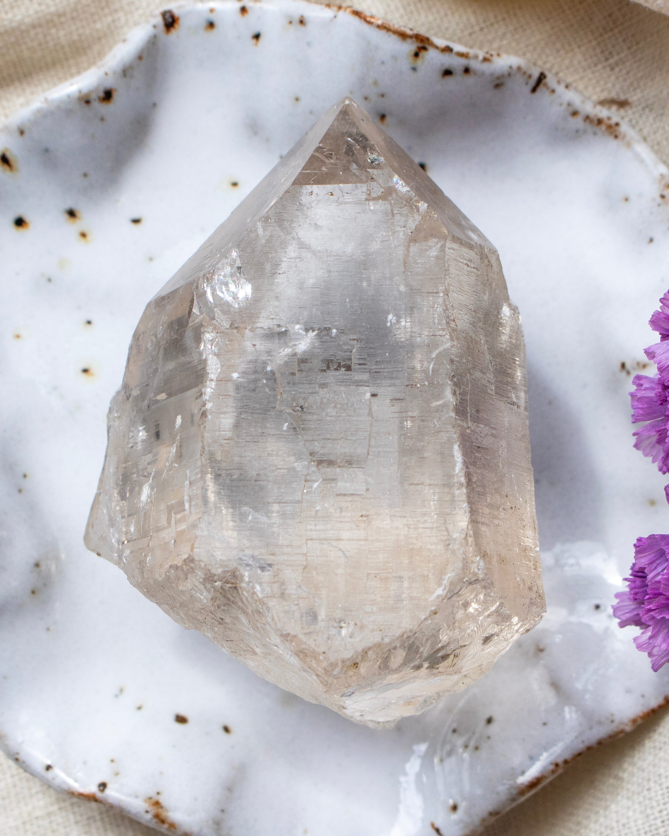 Crystal on a white marble surface with purple flowers