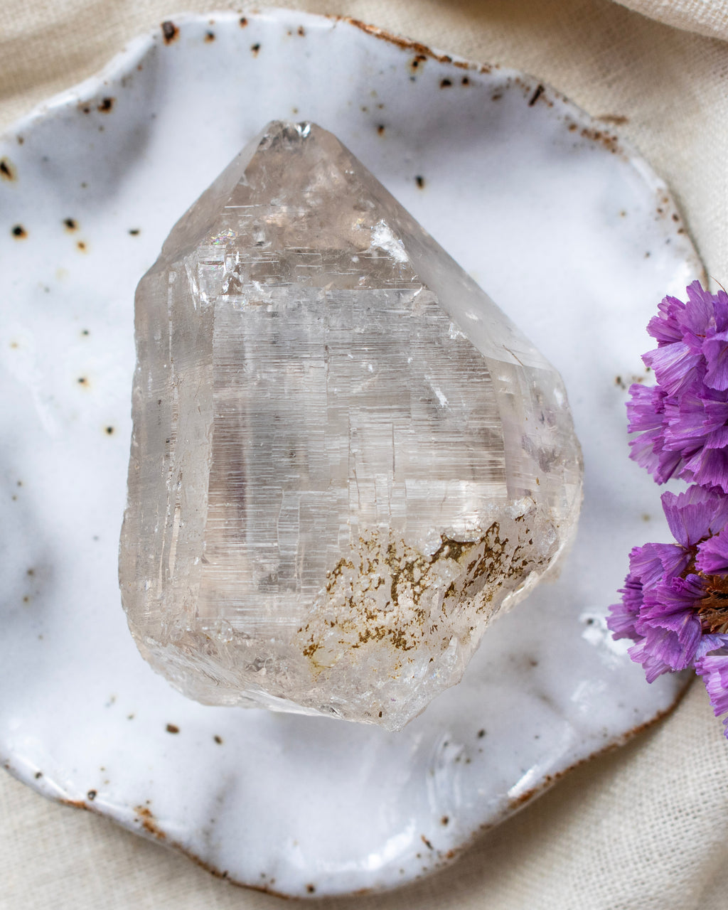 Clear crystal on a white ceramic dish with purple flowers