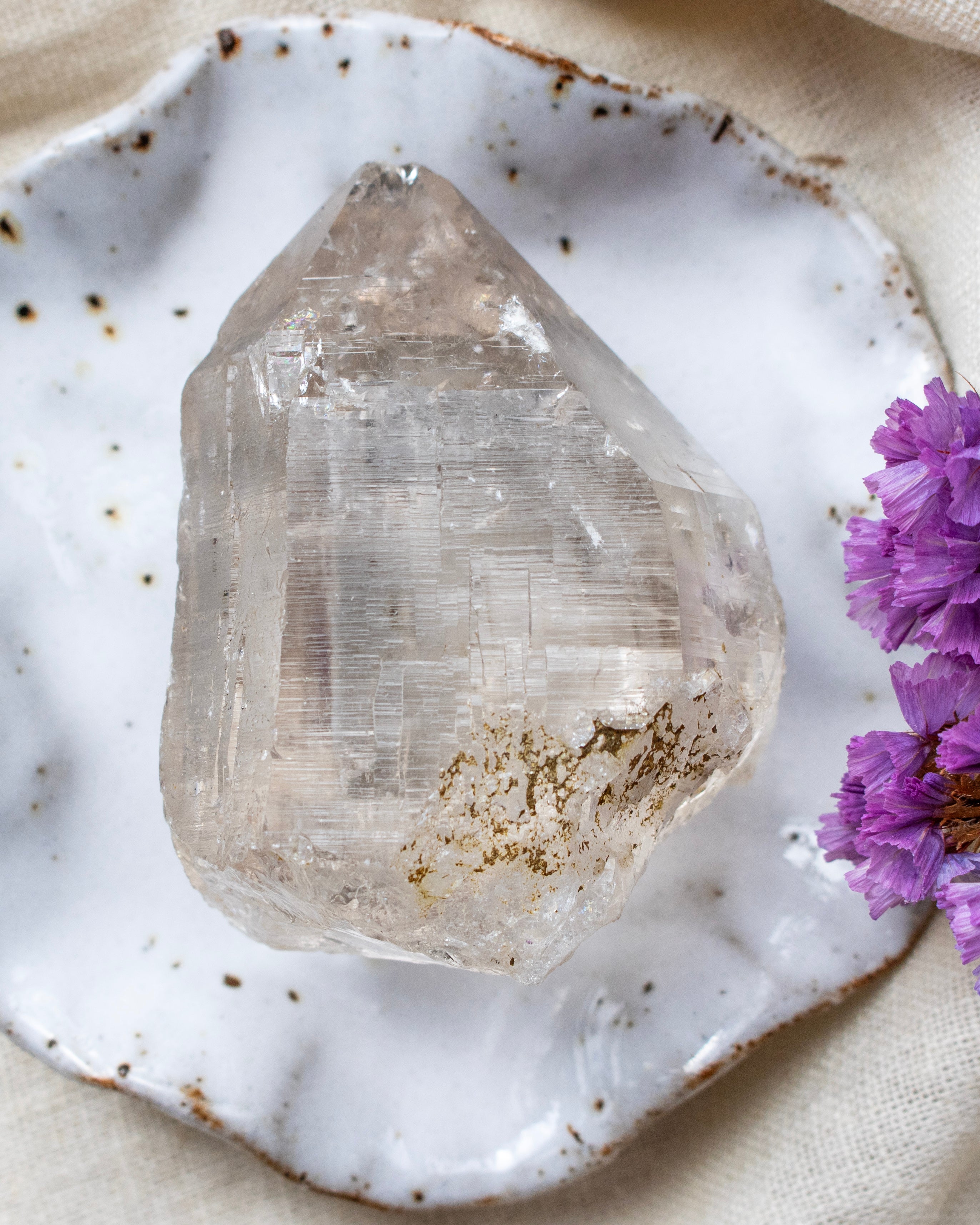Clear crystal on a white ceramic dish with purple flowers