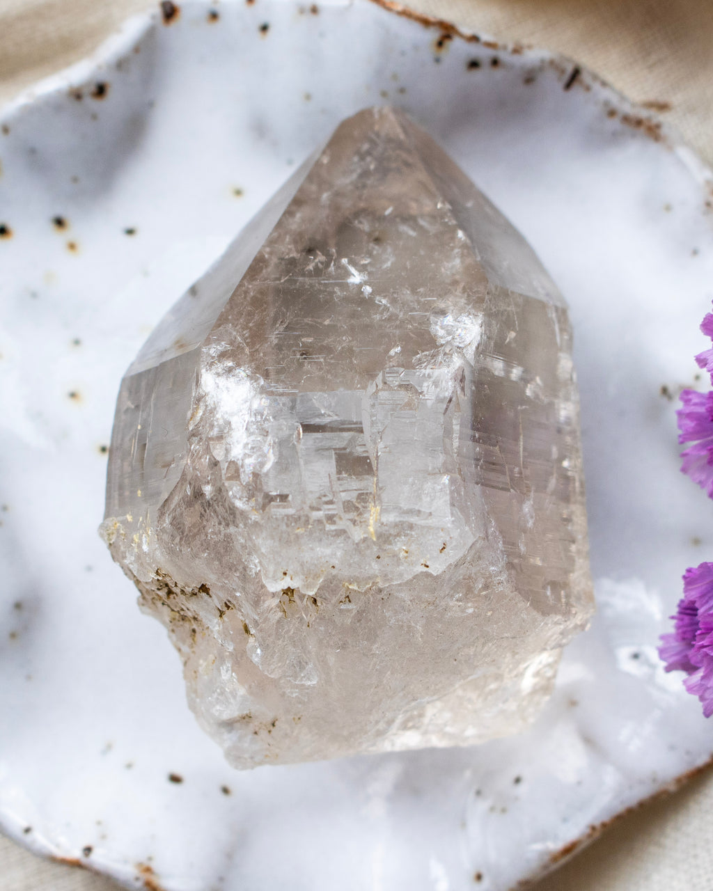 Clear crystal on a textured white surface with purple flowers
