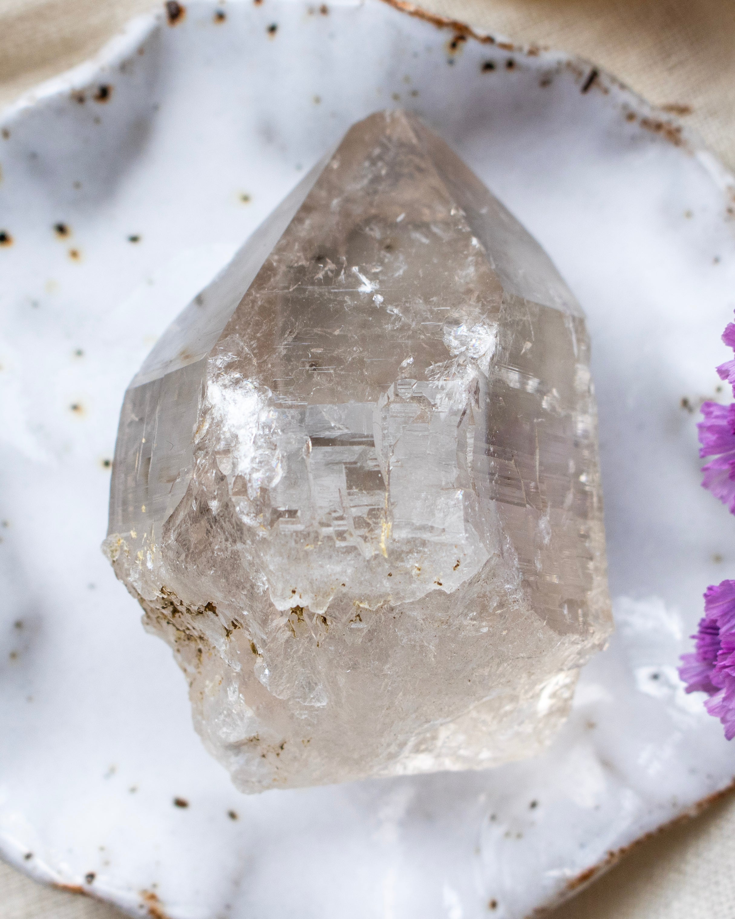 Clear crystal on a textured white surface with purple flowers