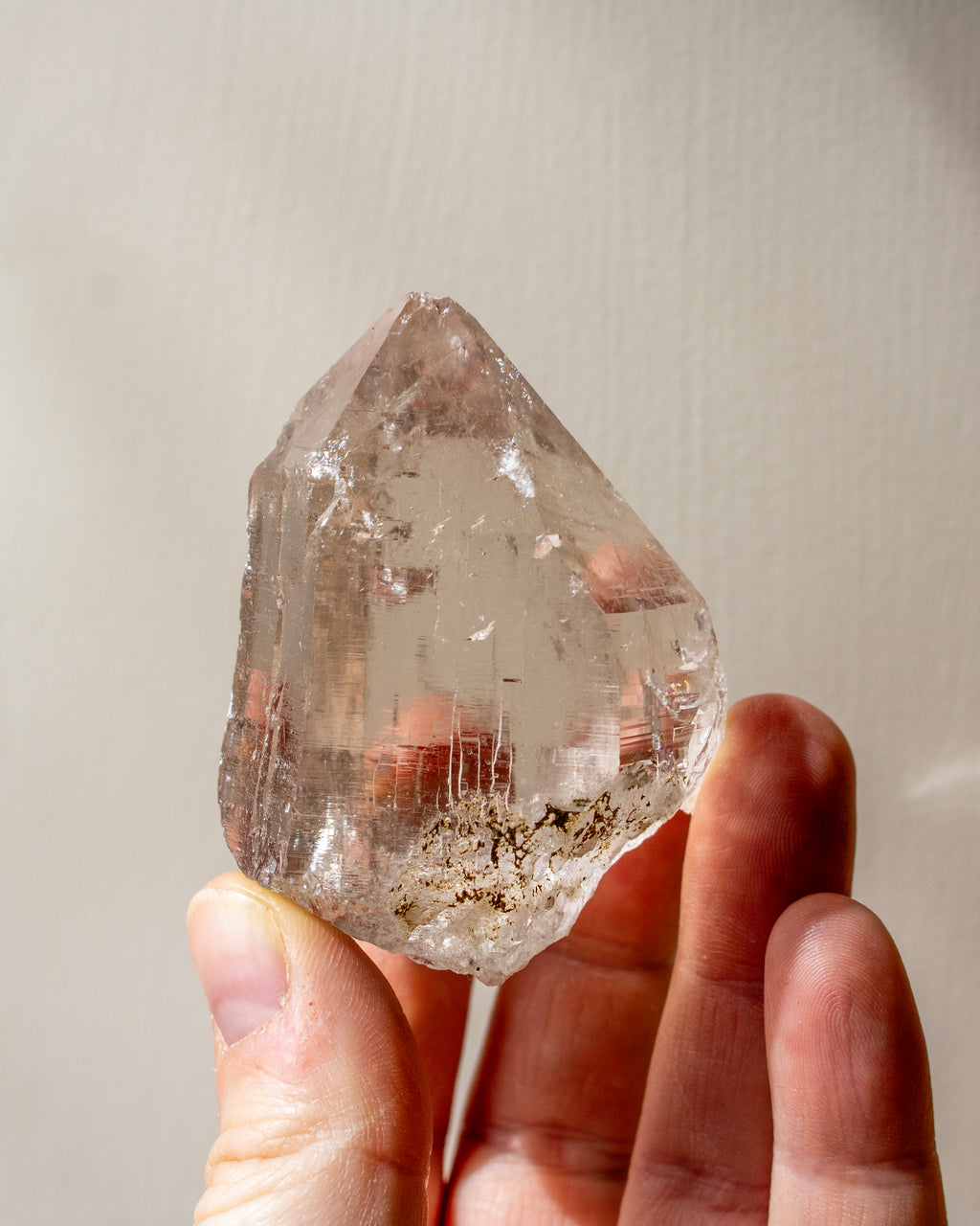 Clear crystal held in a hand against a neutral background