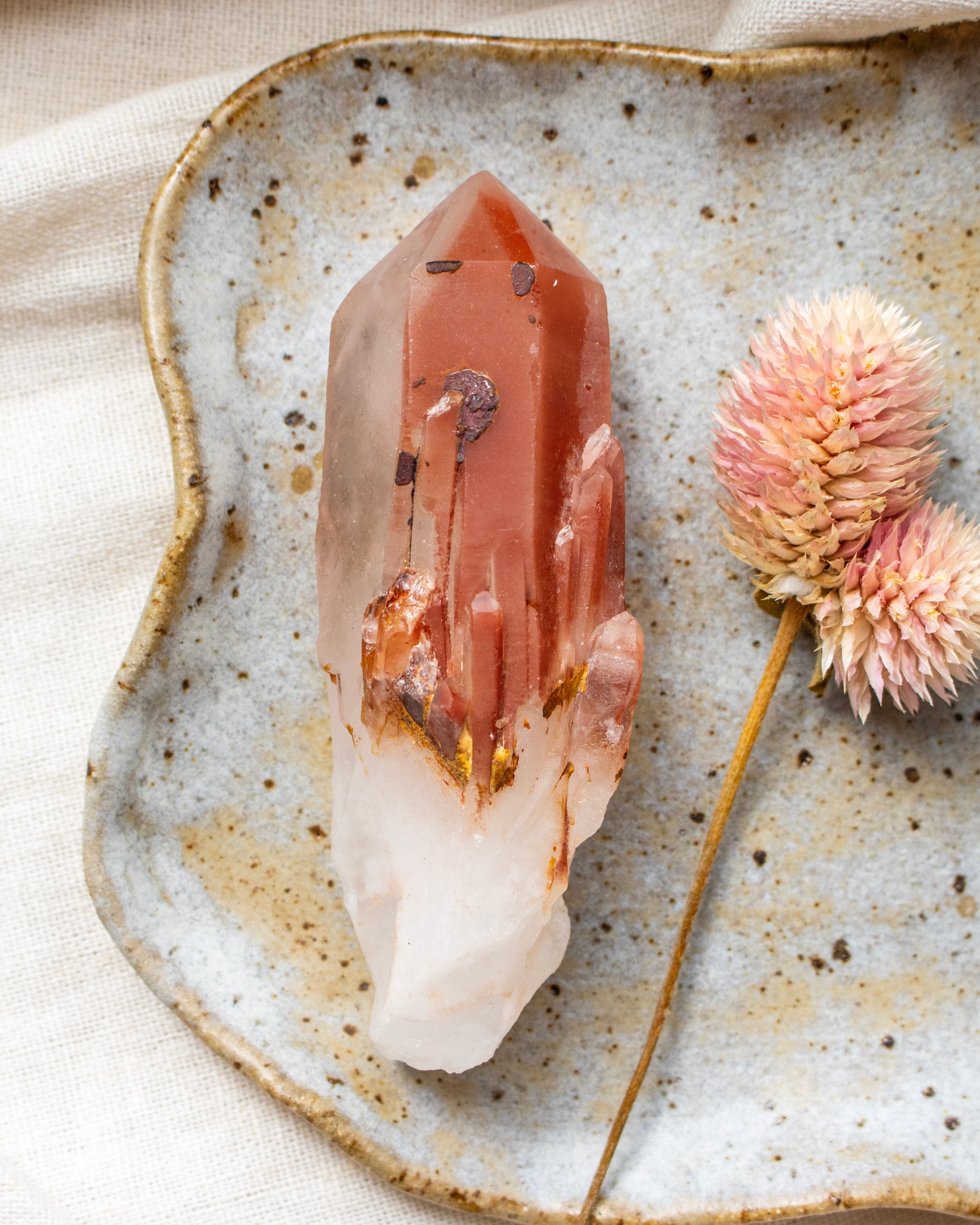 Crystal on a textured ceramic plate with dried flowers