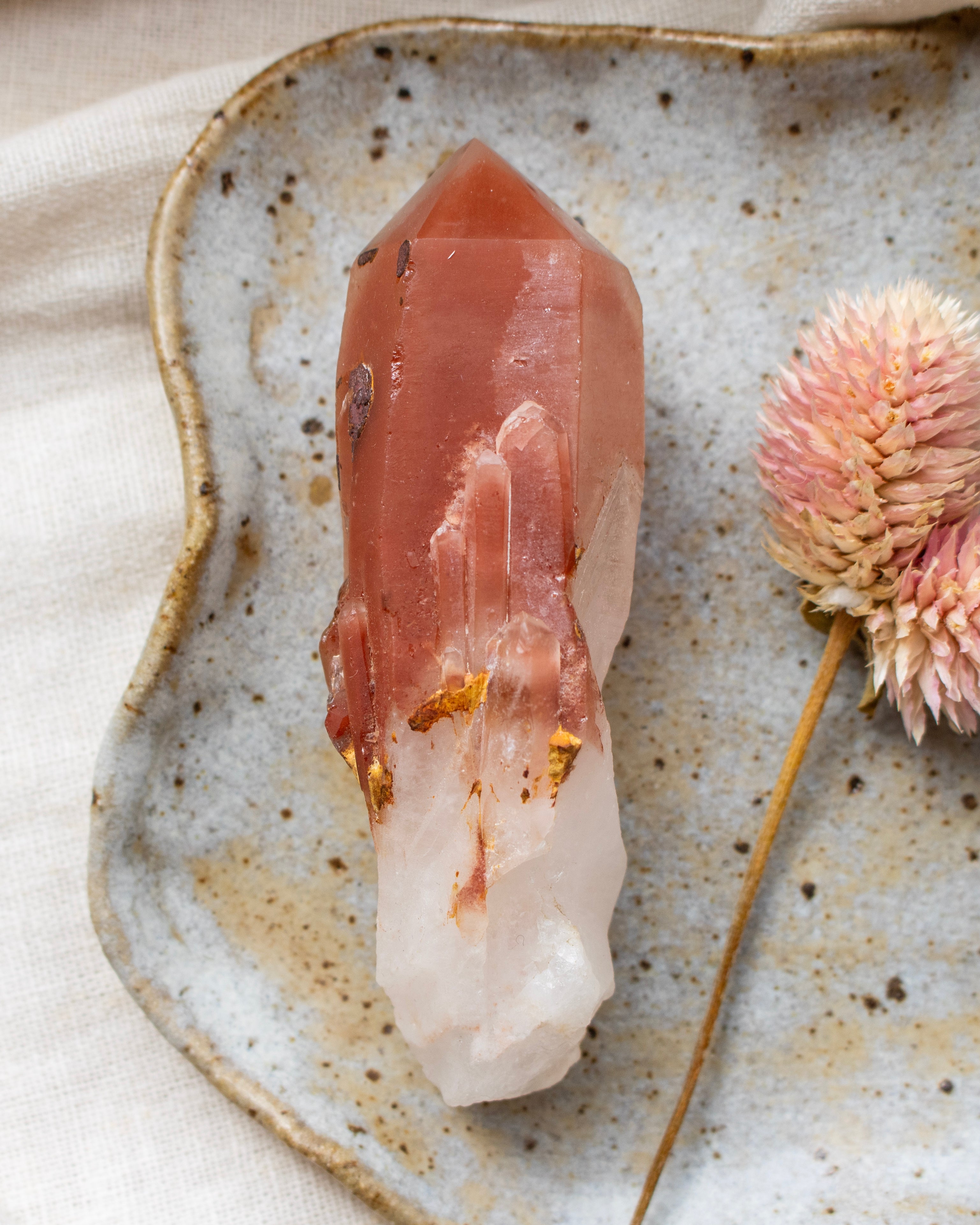Crystal on a textured ceramic plate with a dried flower