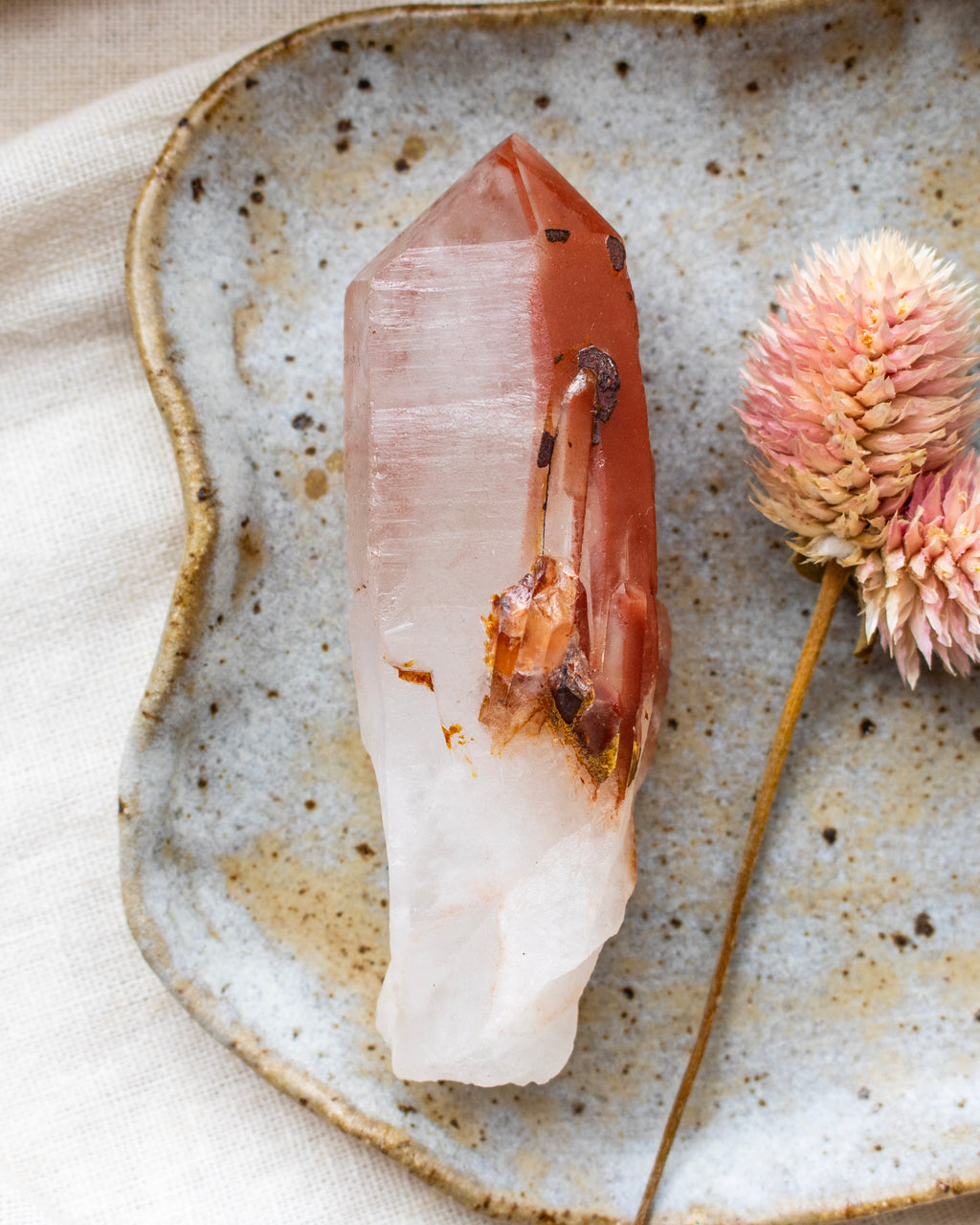 Crystal on a textured ceramic plate with a dried flower