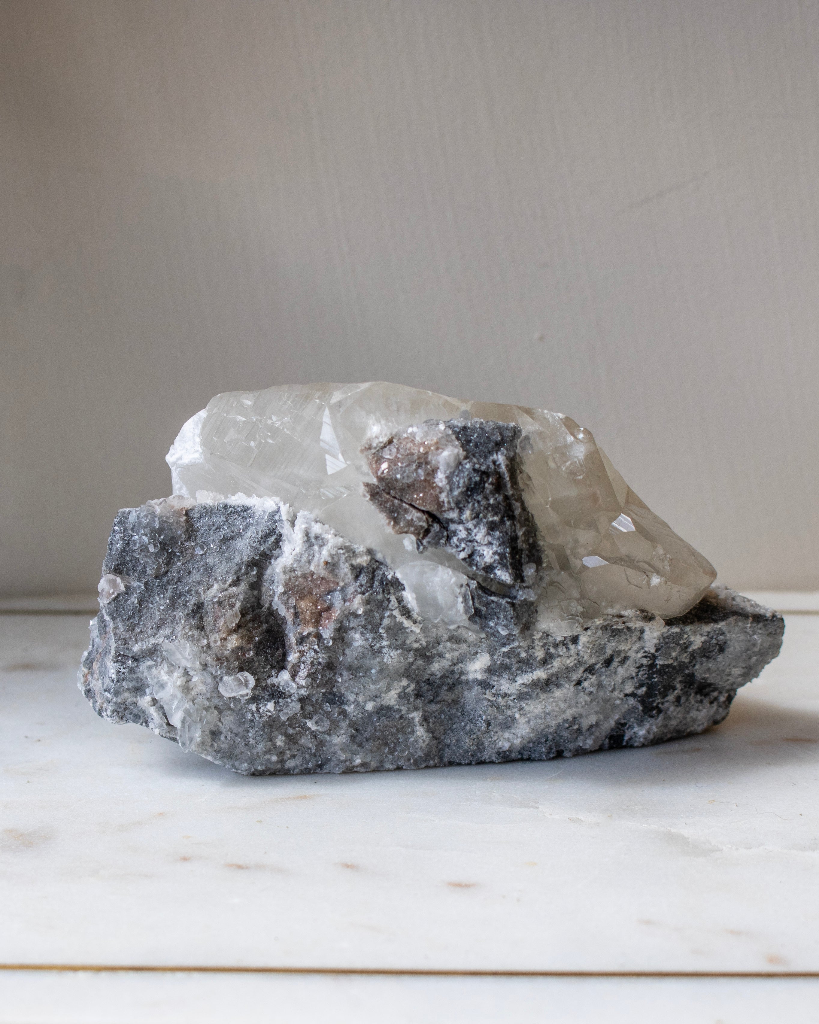 Raw crystal rock on a marble surface with a neutral background