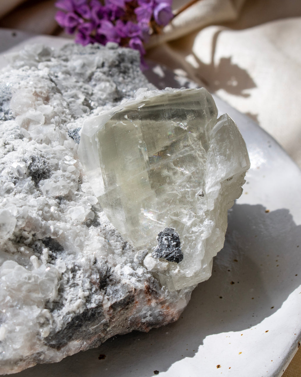 Crystal rock with a purple flower on a white surface