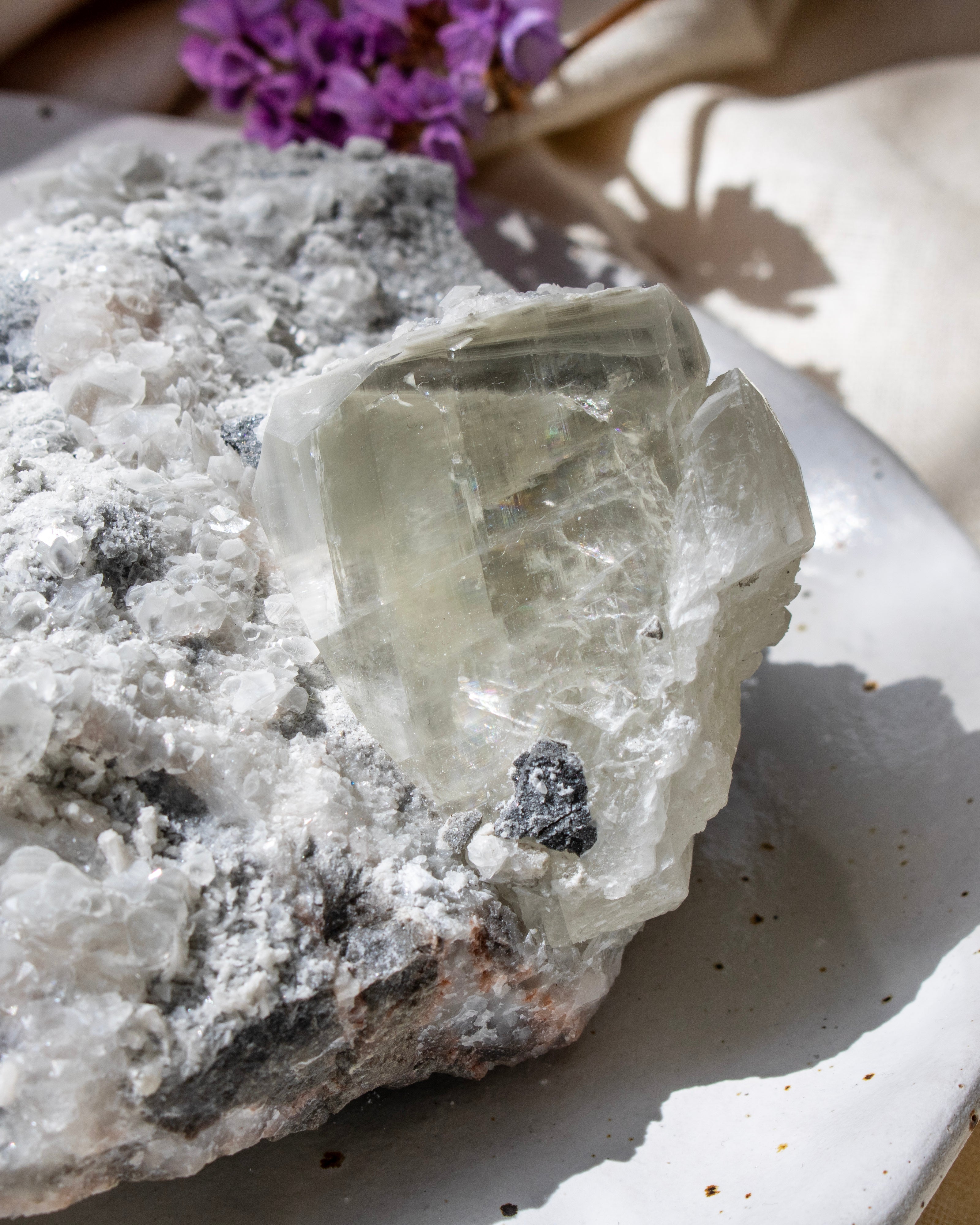 Crystal rock with a purple flower on a white surface