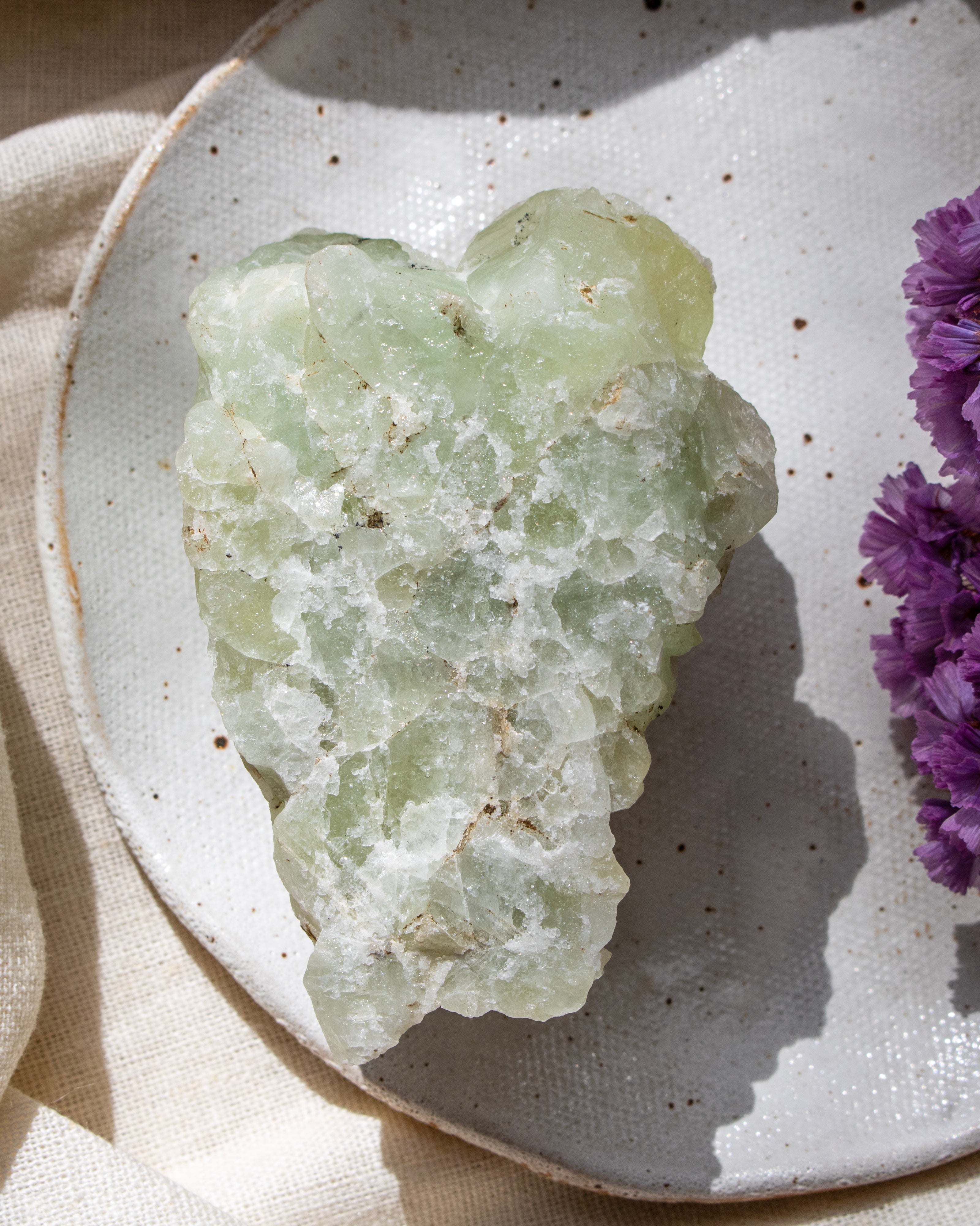 Green crystal on a white plate with purple flowers
