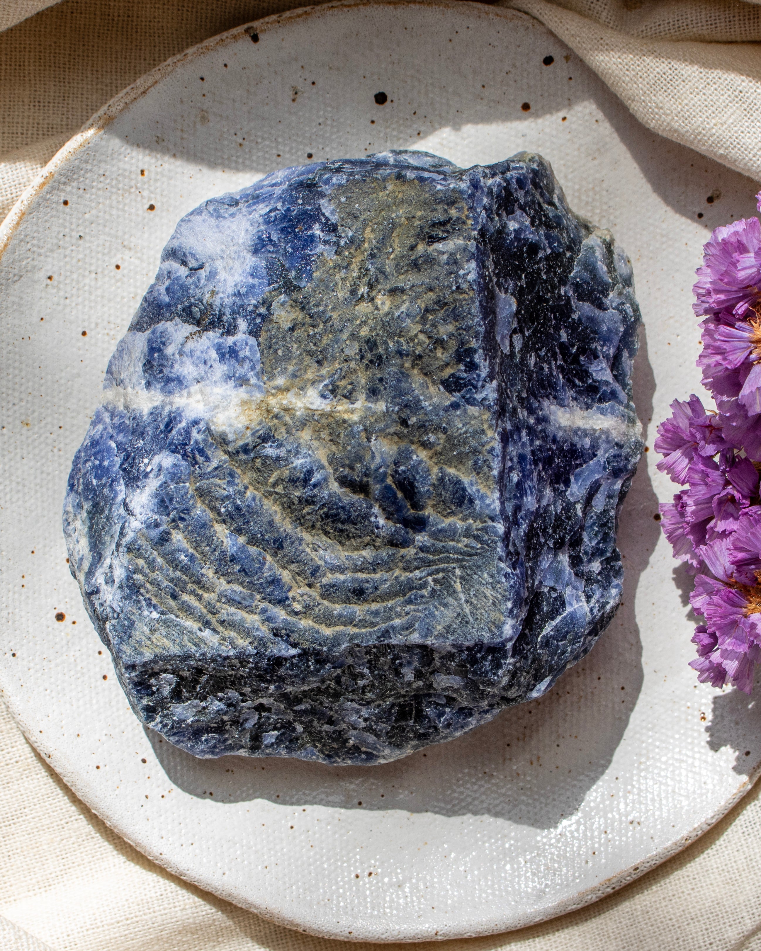 Blue stone on a textured white plate with purple flowers