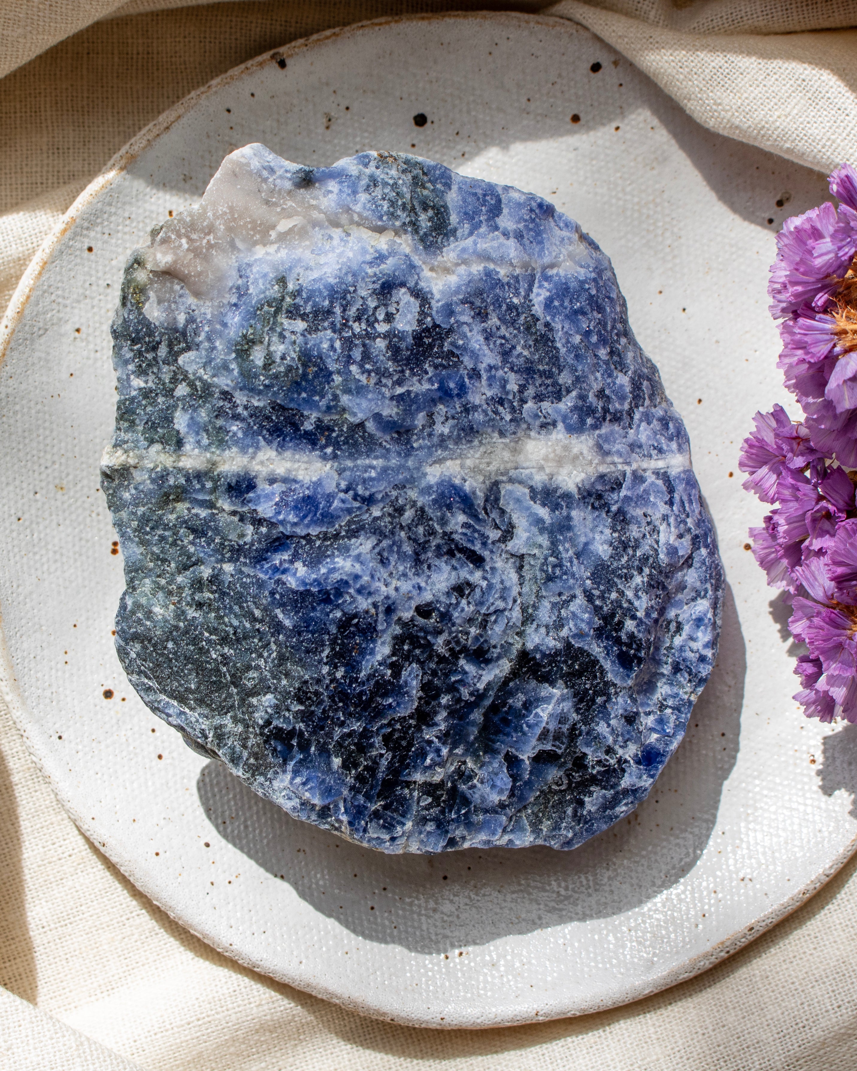 Blue and white crystal rock on a white plate with purple flowers