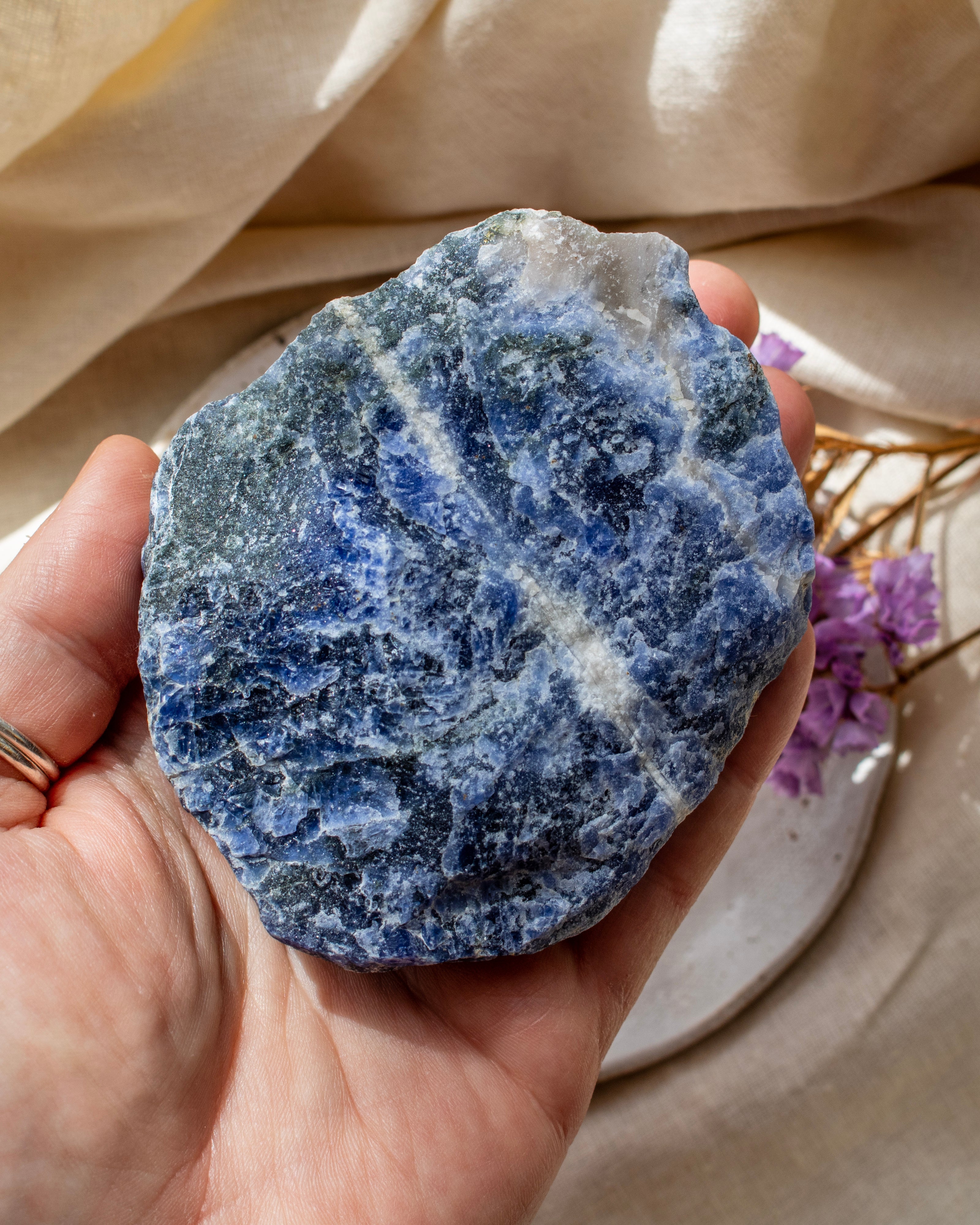 Hand holding a blue and white stone with a soft beige background