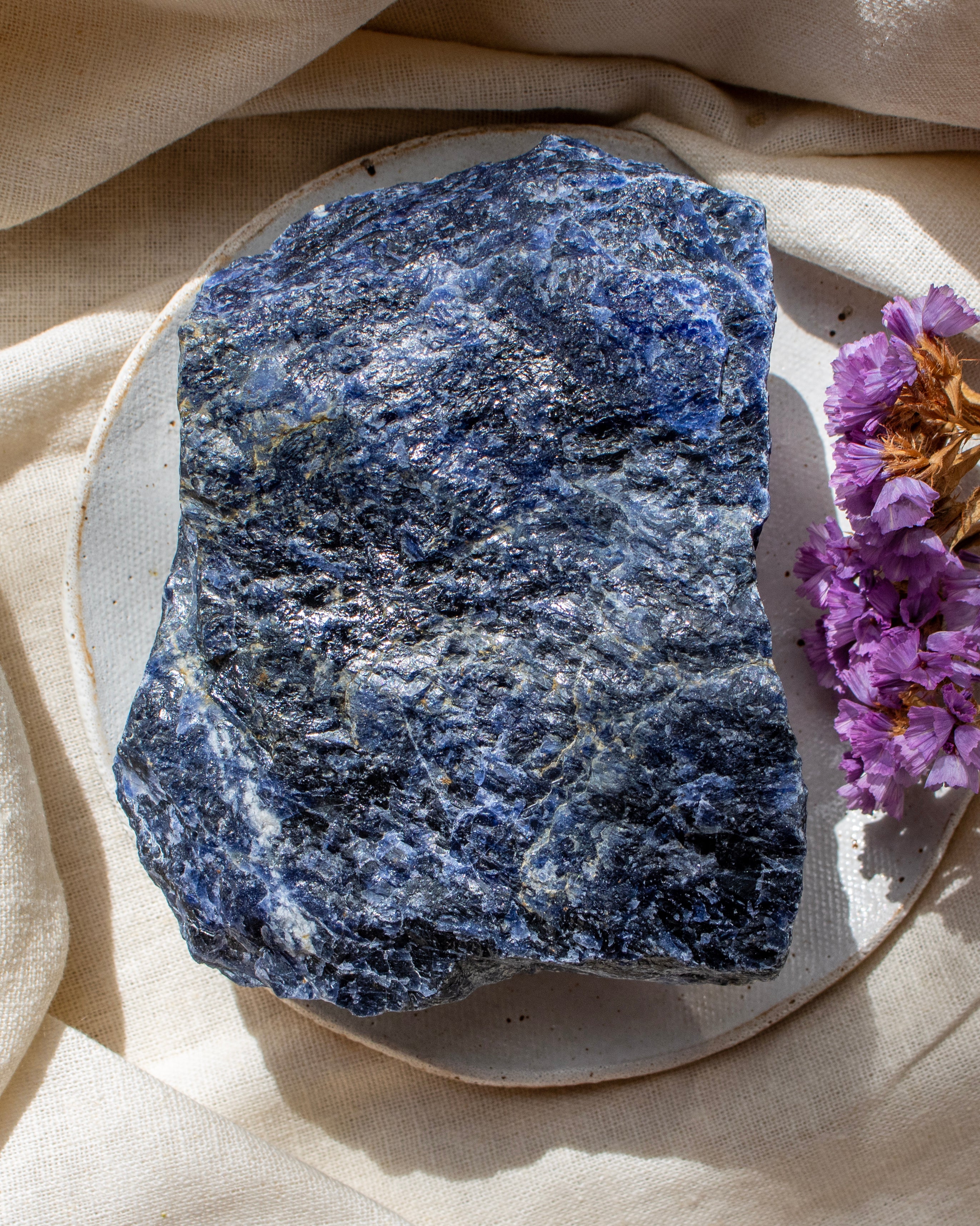Blue stone on a beige surface with purple flowers
