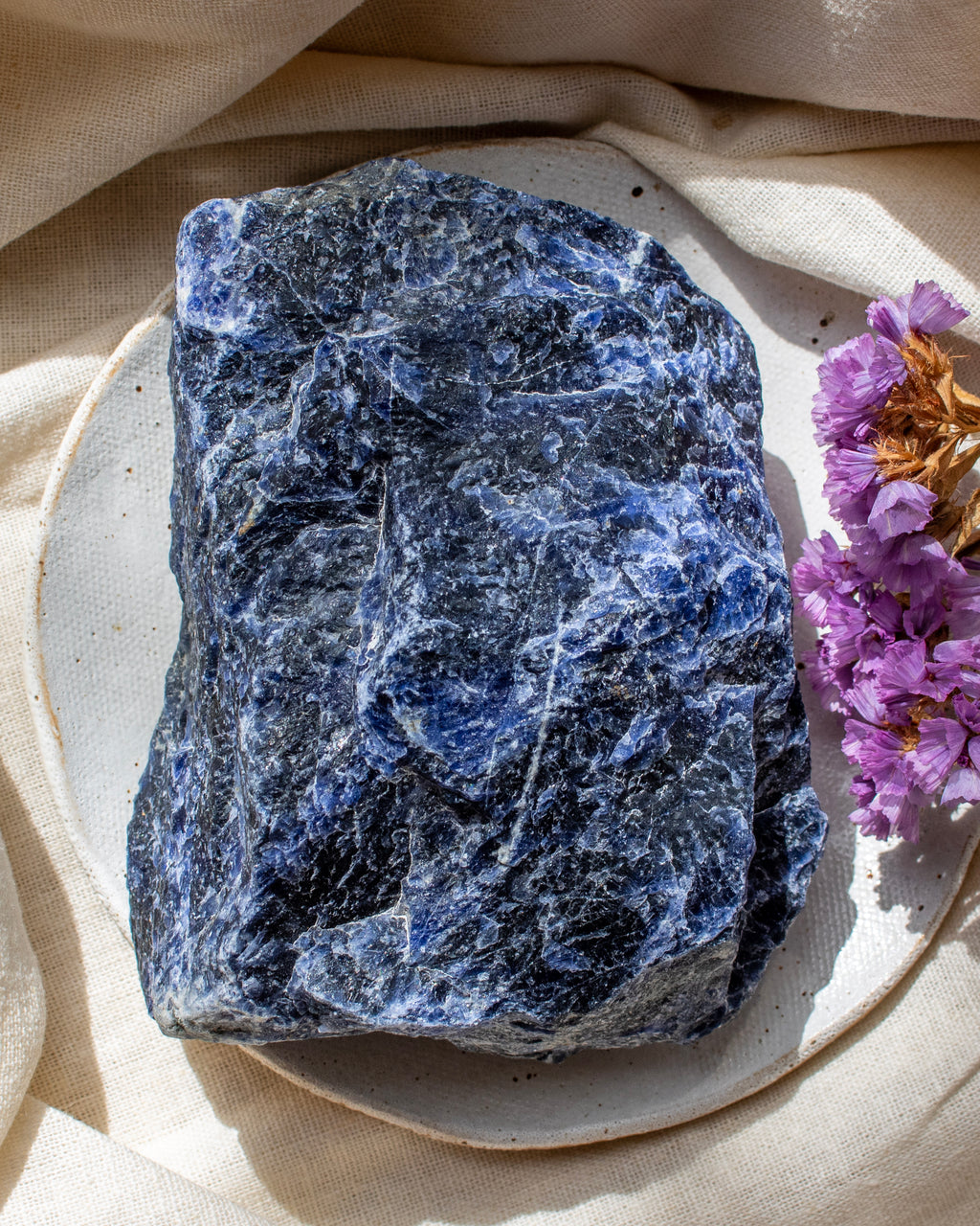Blue stone on a beige plate with purple flowers