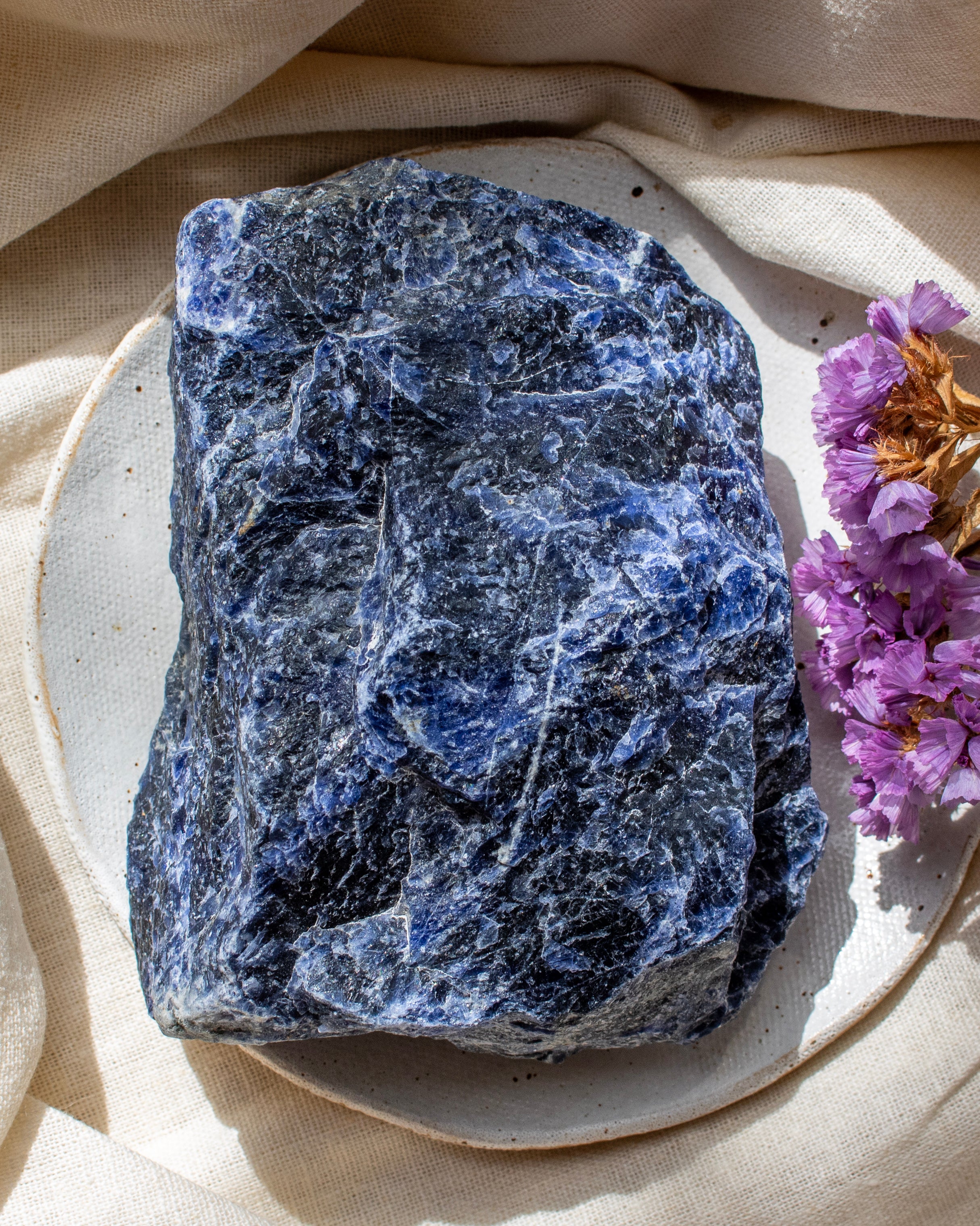 Blue stone on a beige plate with purple flowers