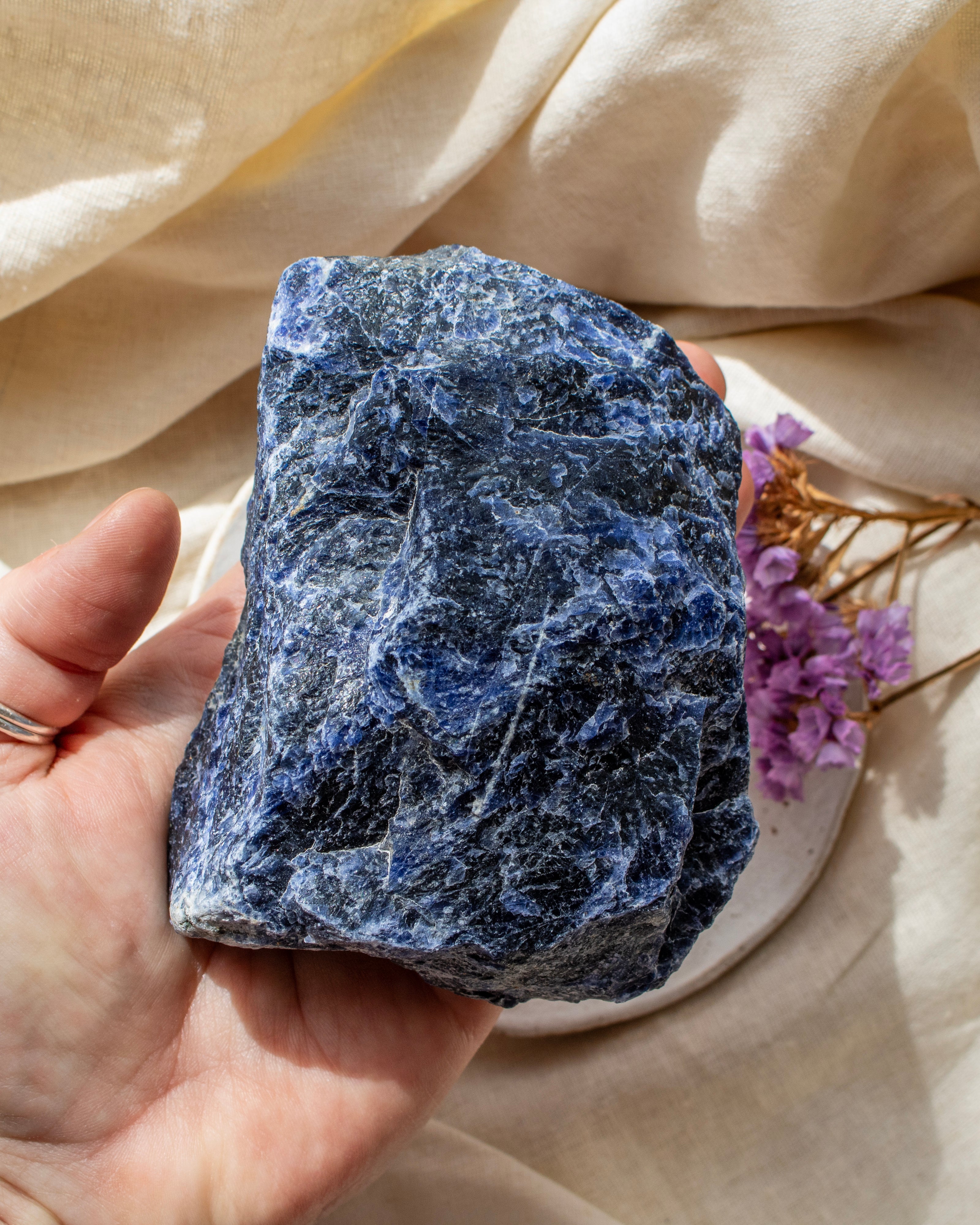 Hand holding a blue stone with a soft beige fabric background