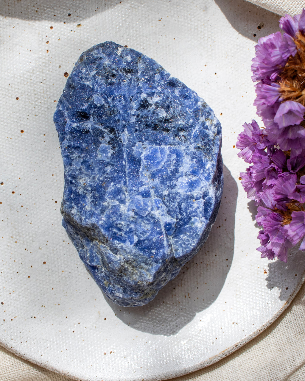 Blue stone on a white plate with purple flowers