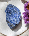 Blue stone on a white plate with purple flowers