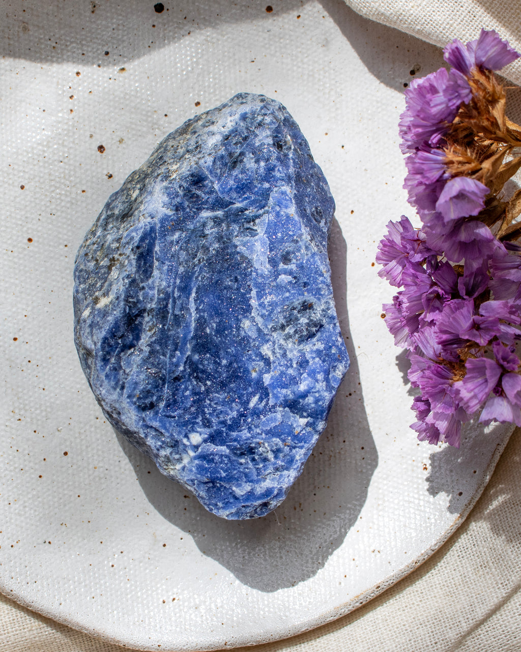 Blue stone on a white plate with purple flowers