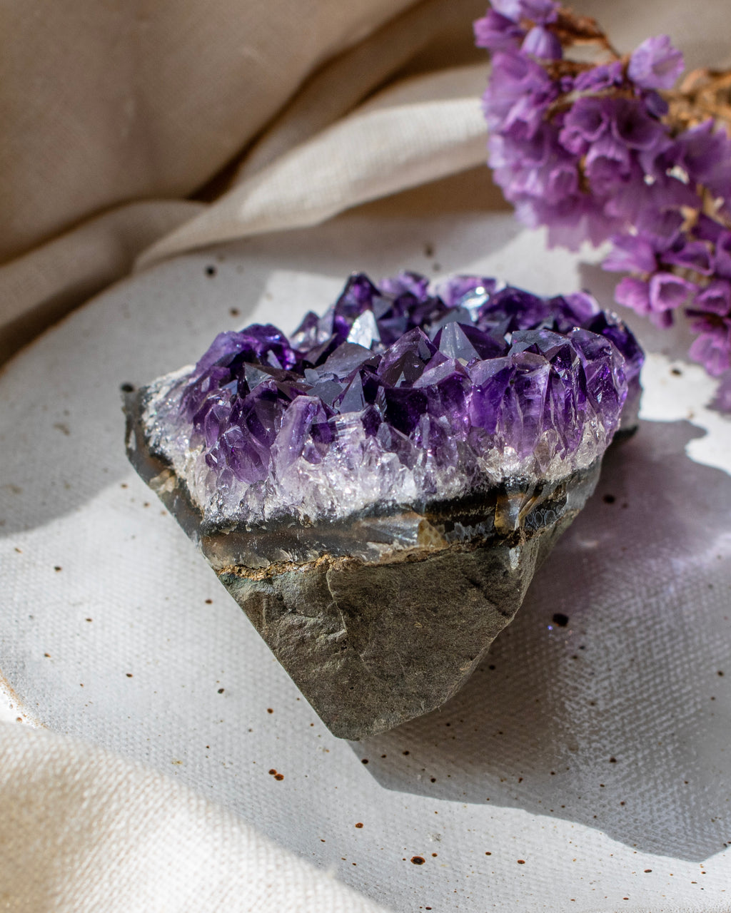 Amethyst crystal on a textured surface with a beige fabric background