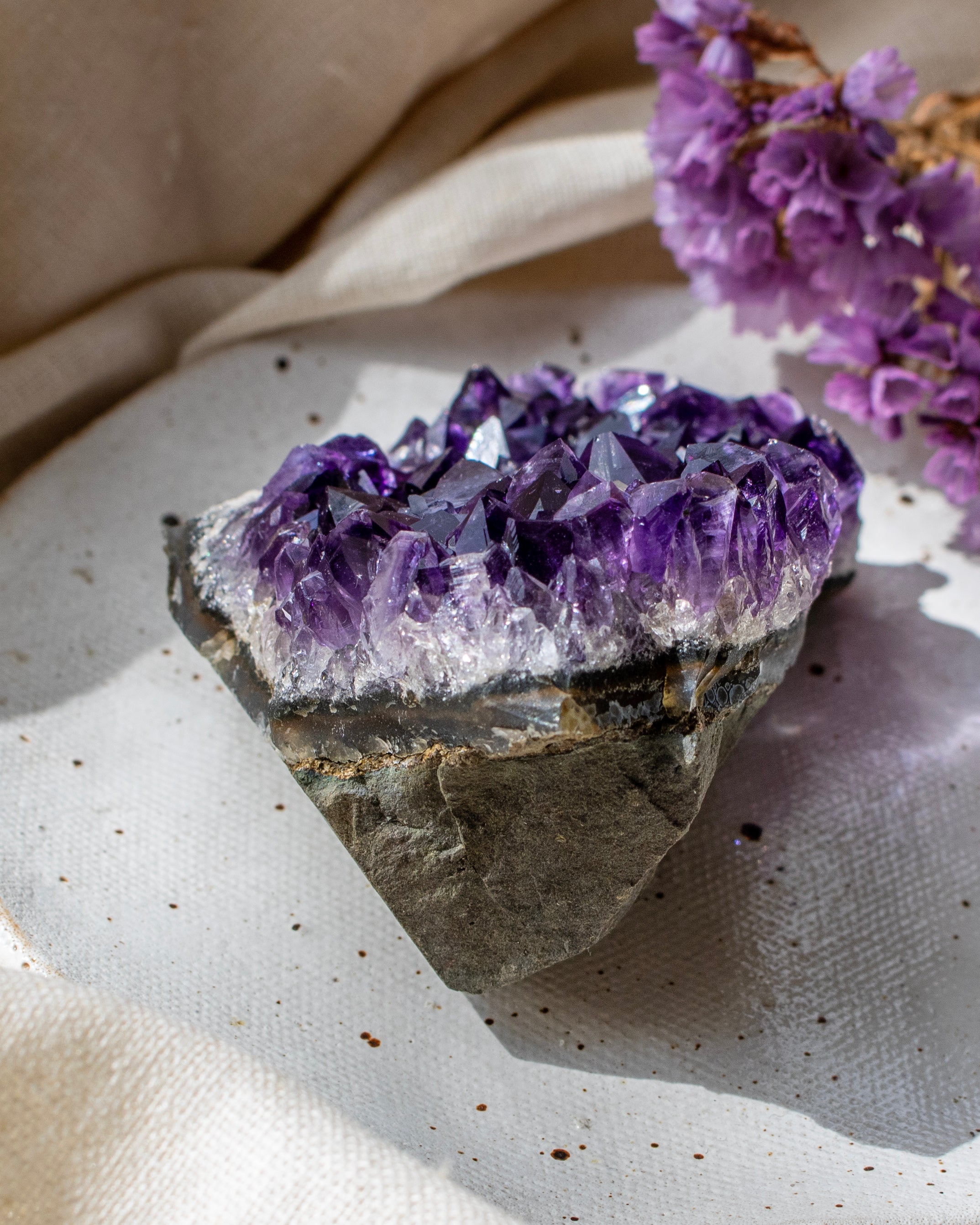 Amethyst crystal on a textured surface with a beige fabric background