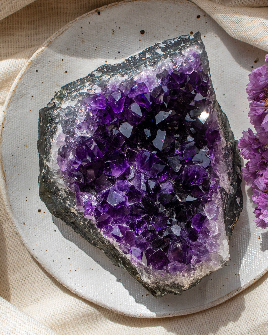 Amethyst crystal on a textured surface with a soft background