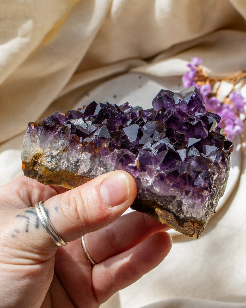 Amethyst crystal held by a hand with a soft background
