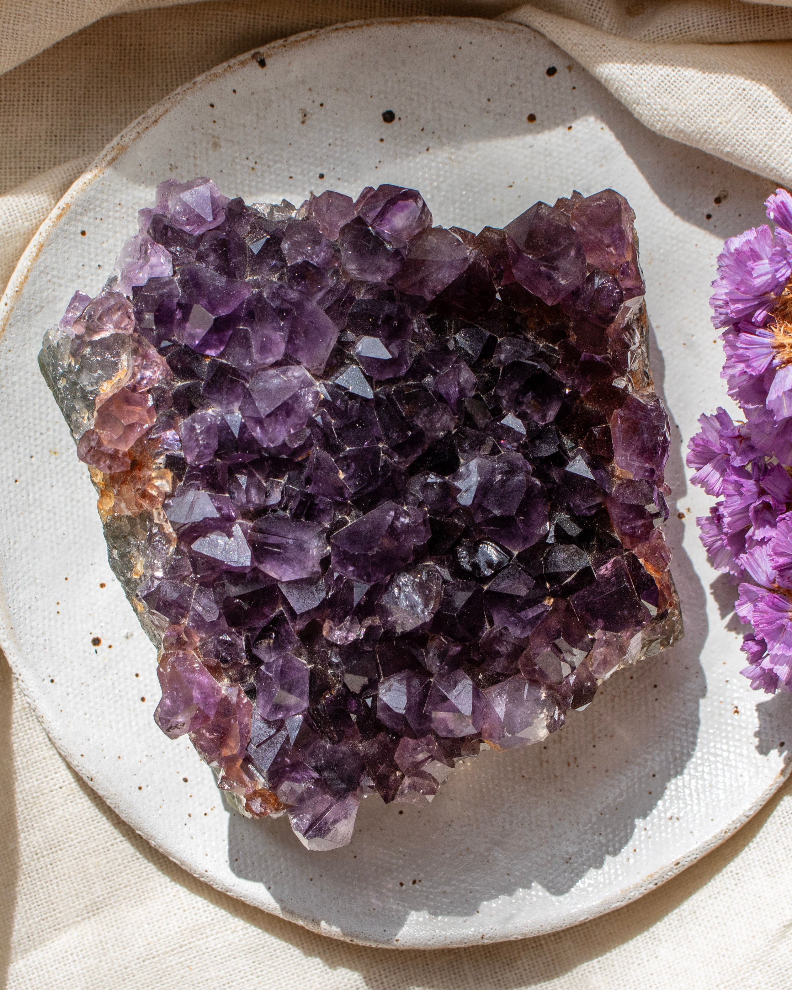 Amethyst crystal cluster on a textured surface with a soft background