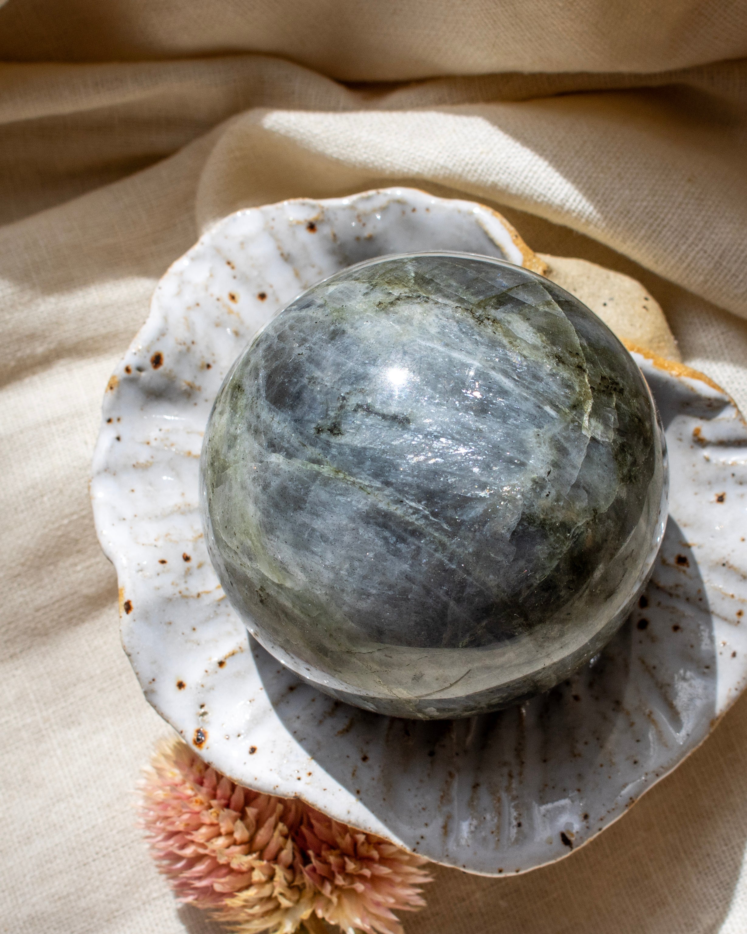Crystal ball on a shell with a beige fabric background