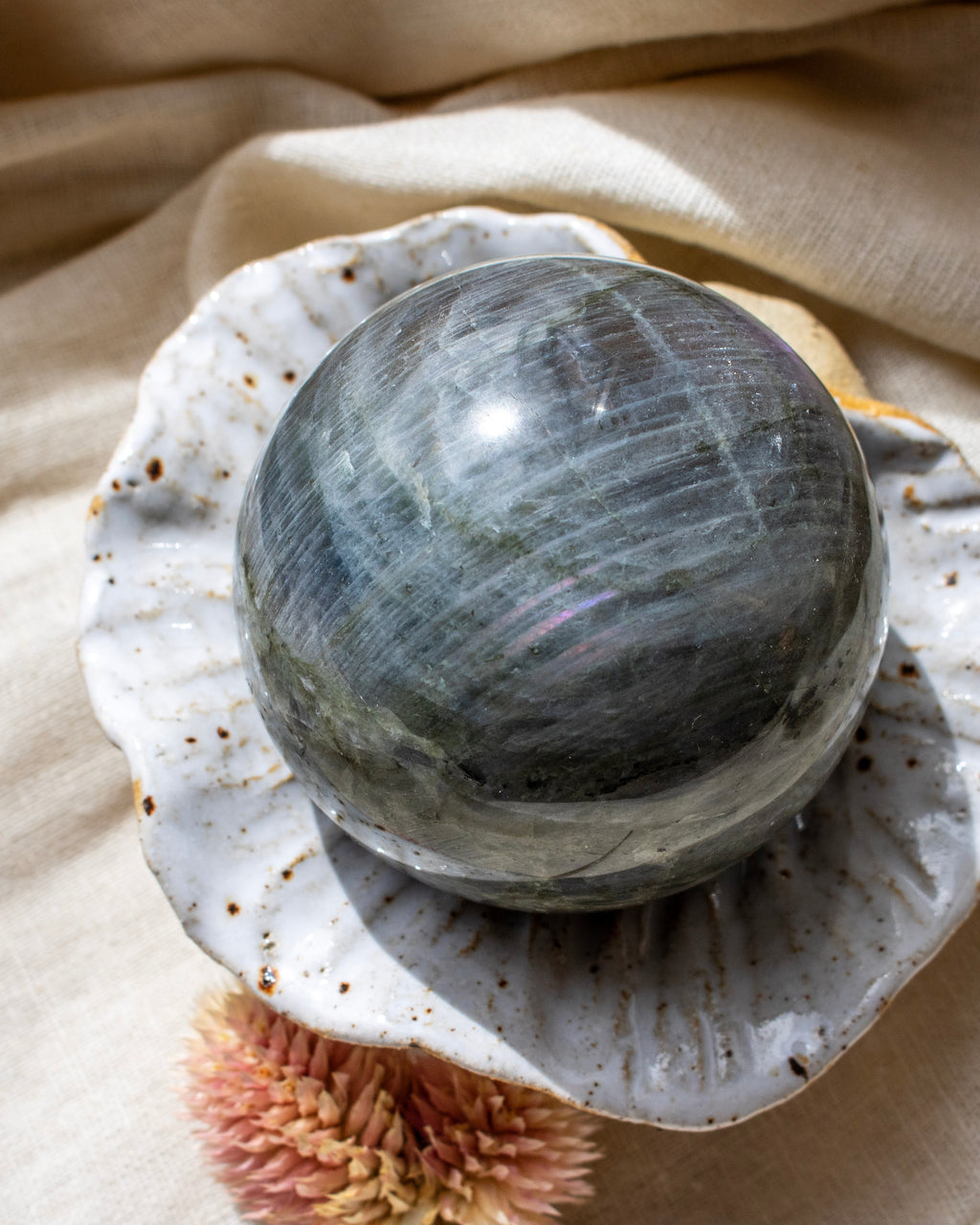 Gray crystal ball on a textured surface with a beige fabric background
