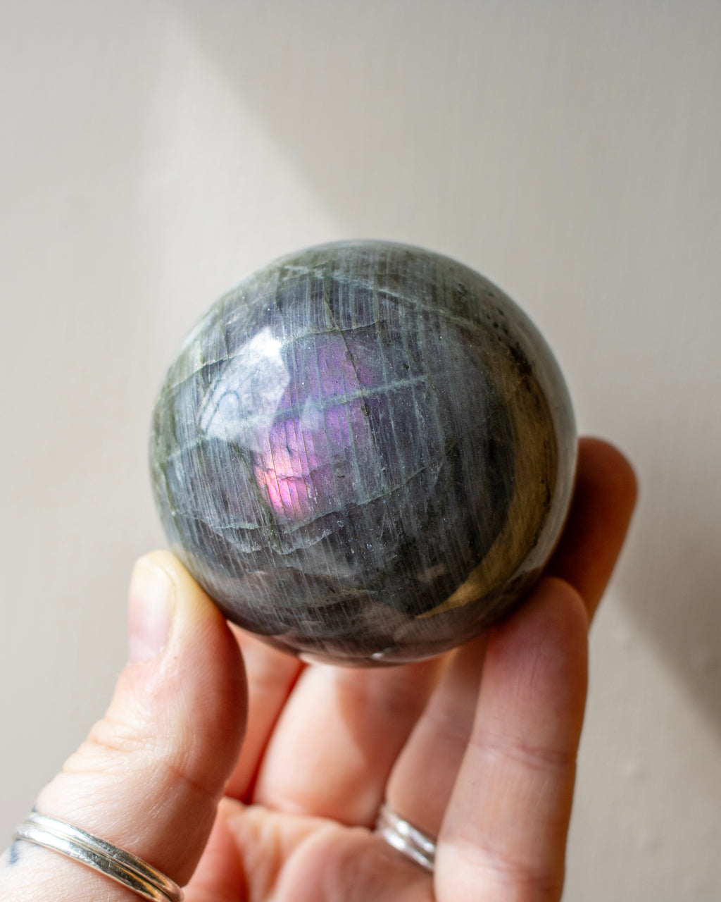 Person holding a rainbow-colored crystal ball against a plain background