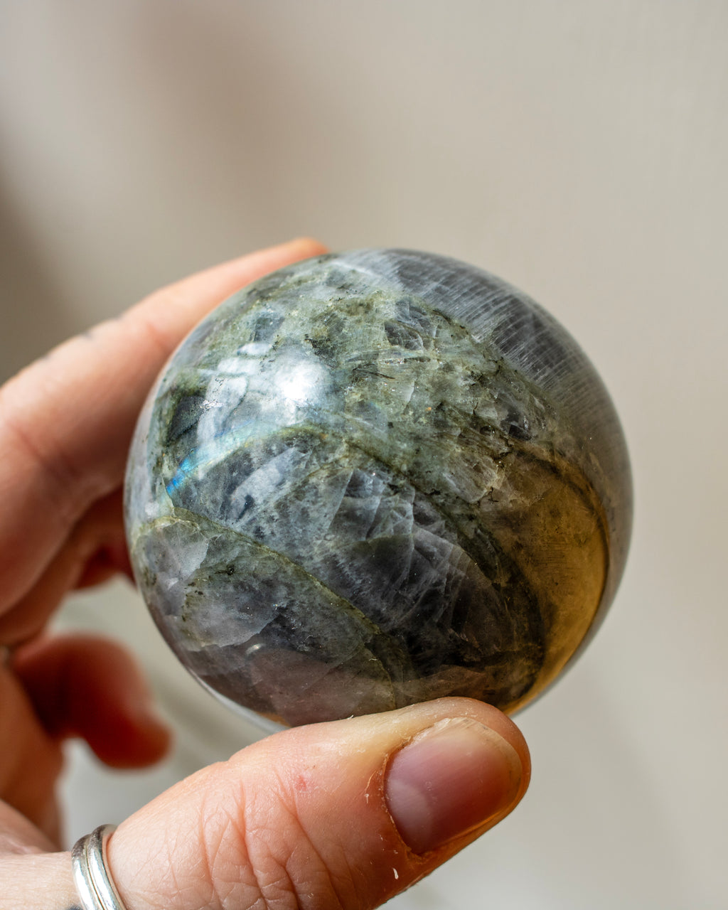 Hand holding a large crystal sphere against a blurred background