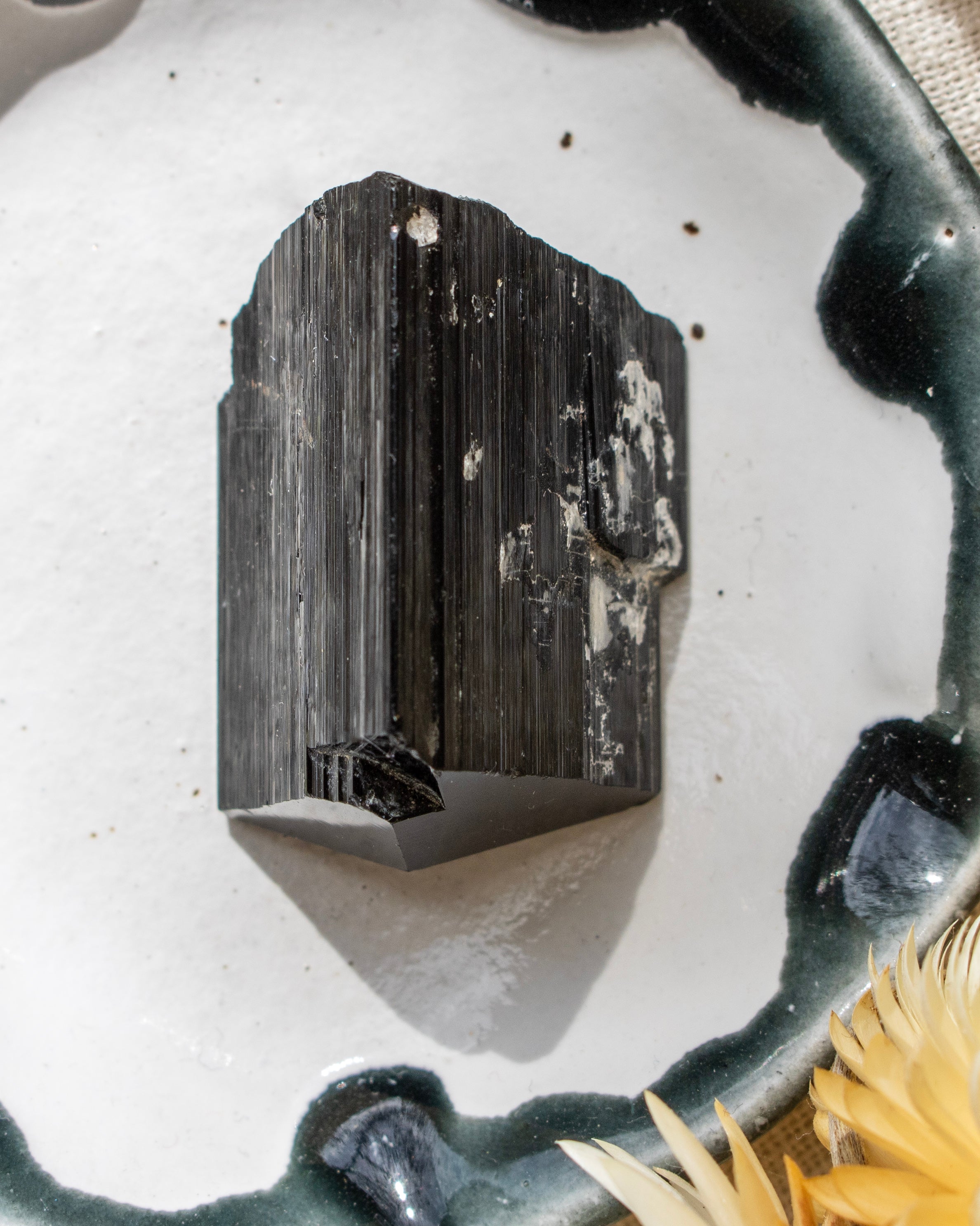 Black crystal on a white surface with a textured background