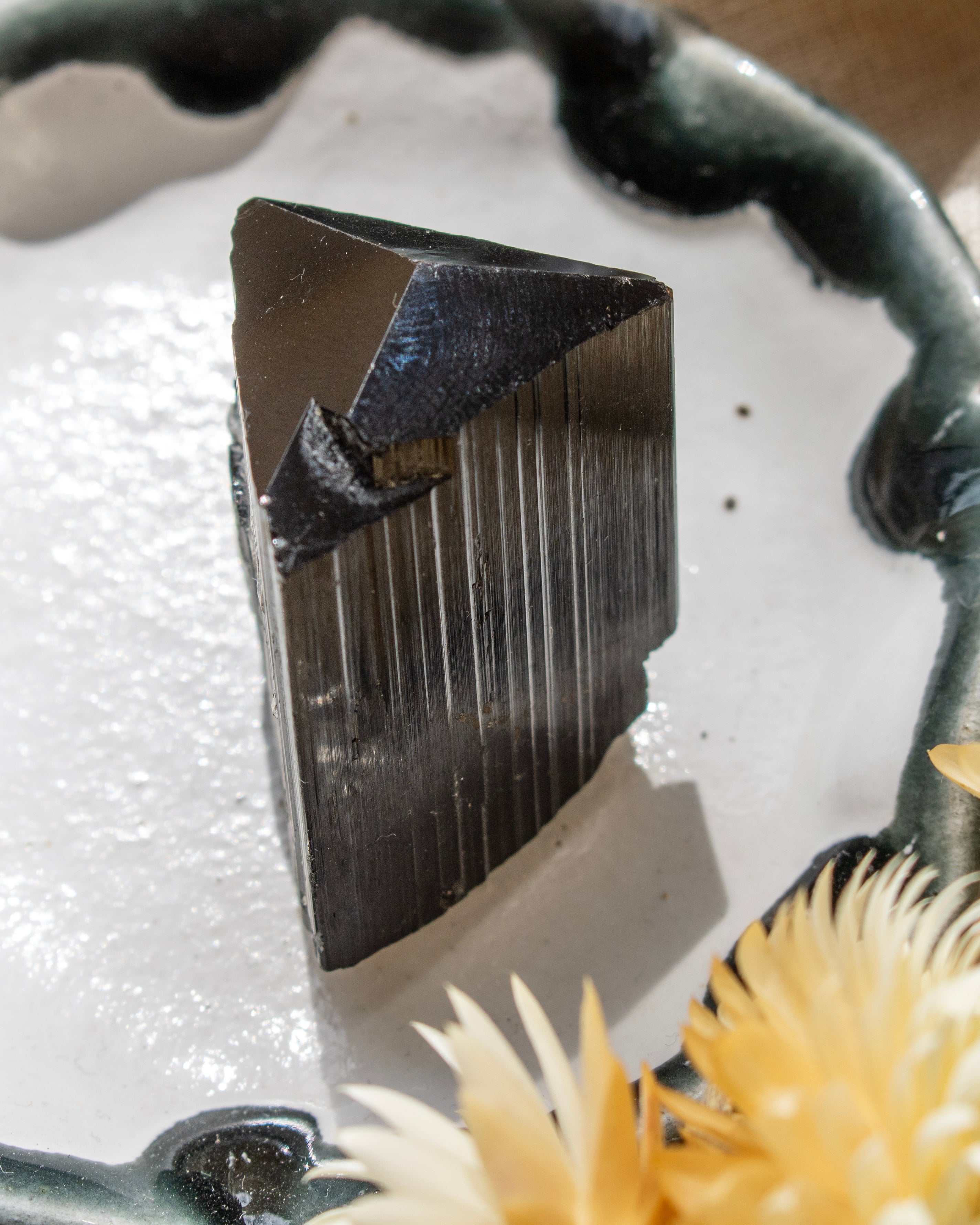 Shiny black crystal on a textured surface with a blurred background
