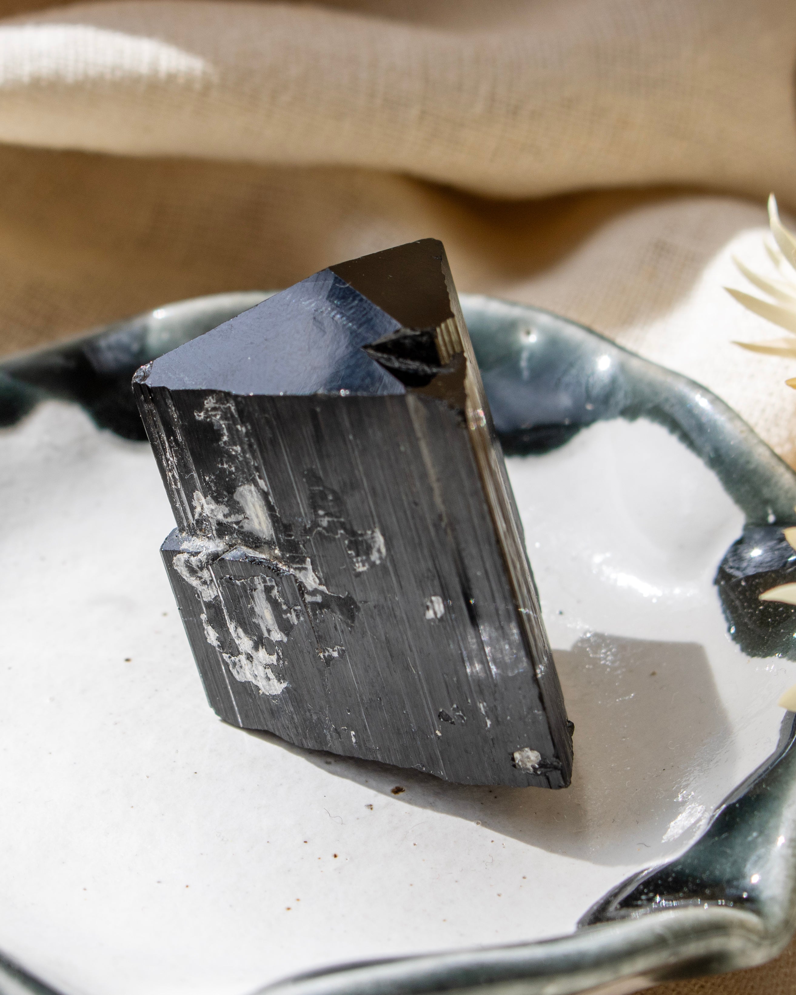 Black crystal on a white dish with a beige background