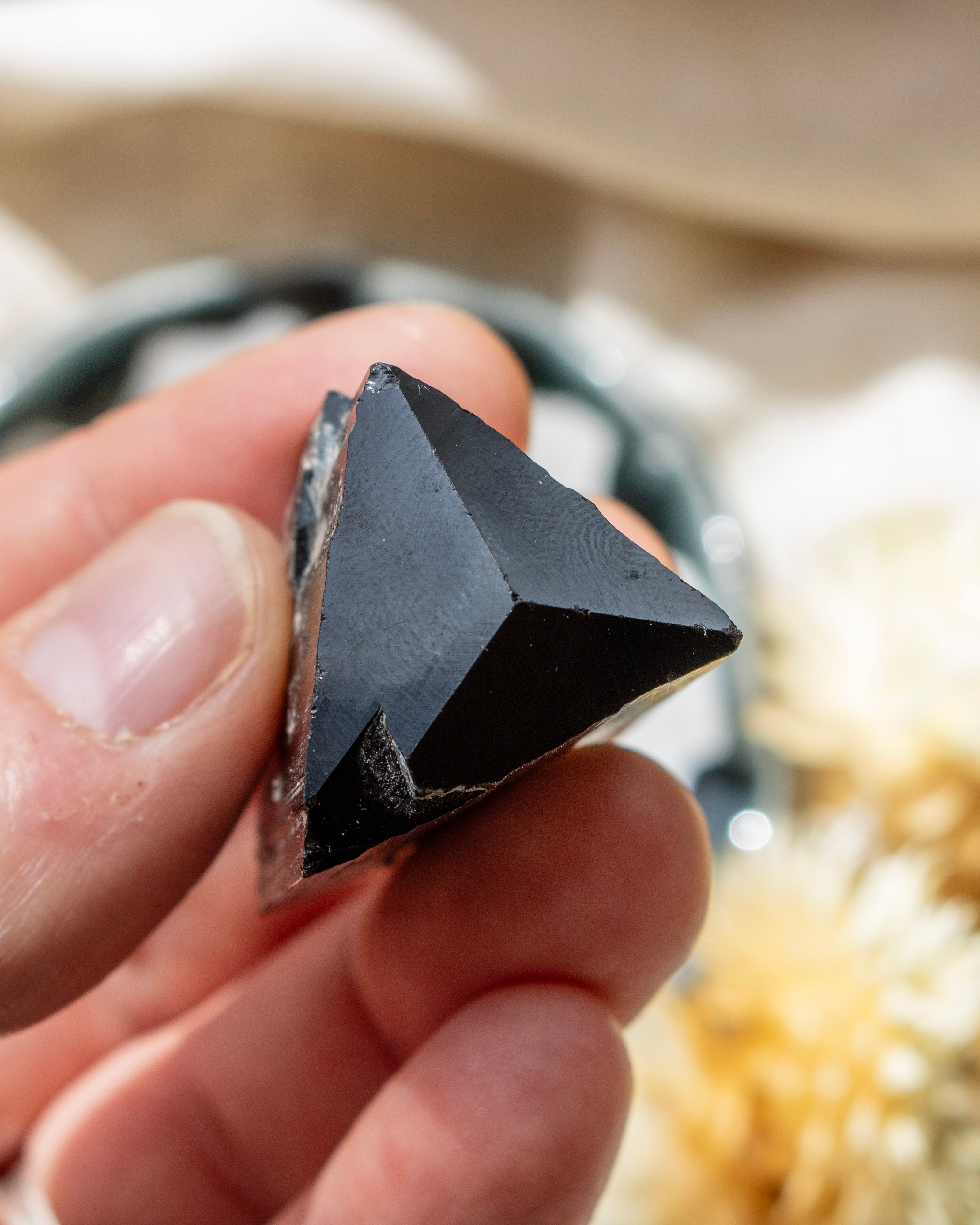 Person holding a triangular stone object with a blurred natural background